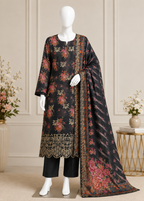 A three-piece women's salwar kameez suit set displayed on a white mannequin. The set includes a black cotton kurta with intricate multicolor floral embroidery and a scalloped gold border, black trousers, and a matching black dupatta with a detailed floral and geometric border.