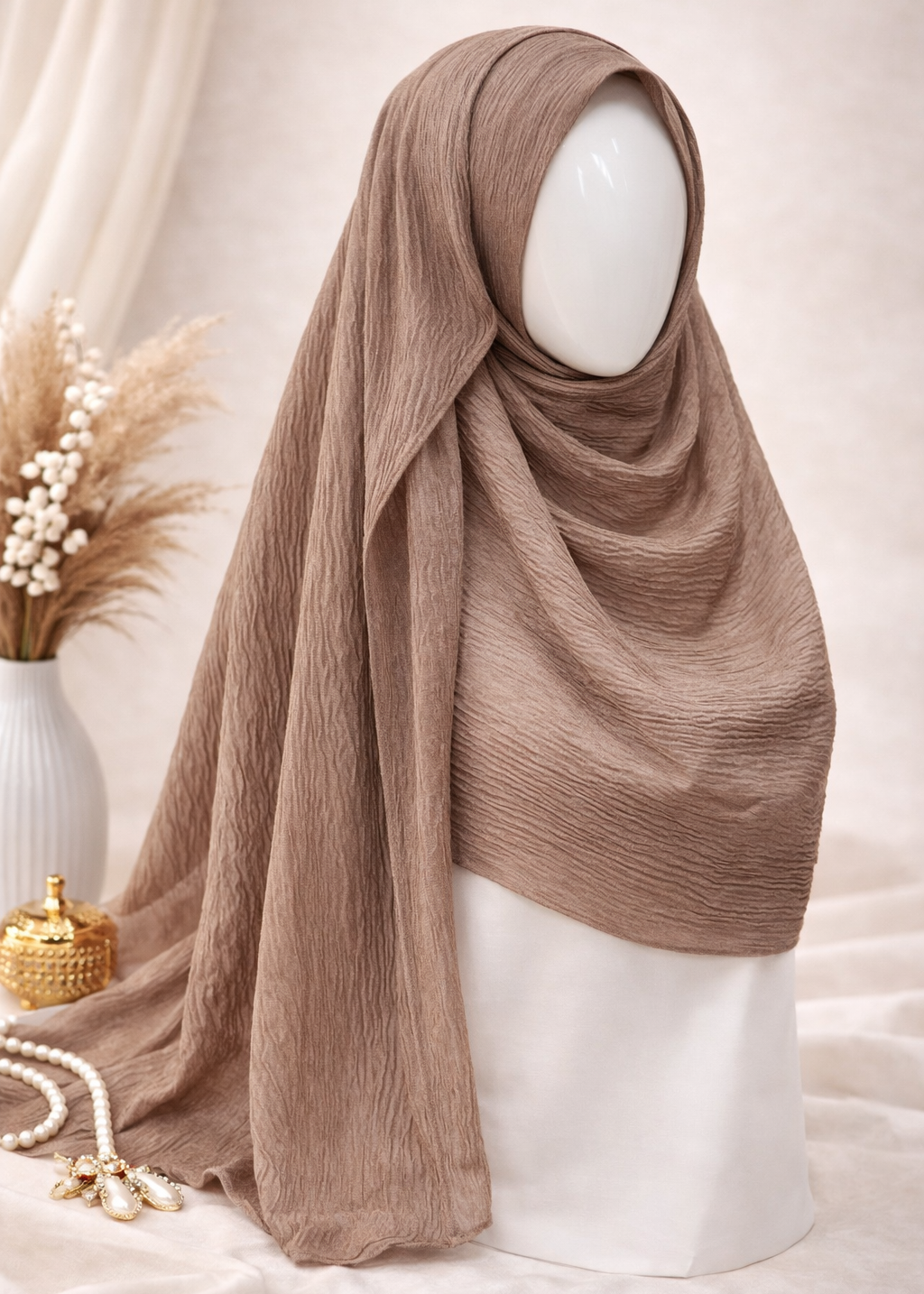Brown hijab on a mannequin head with decorative elements on a light background