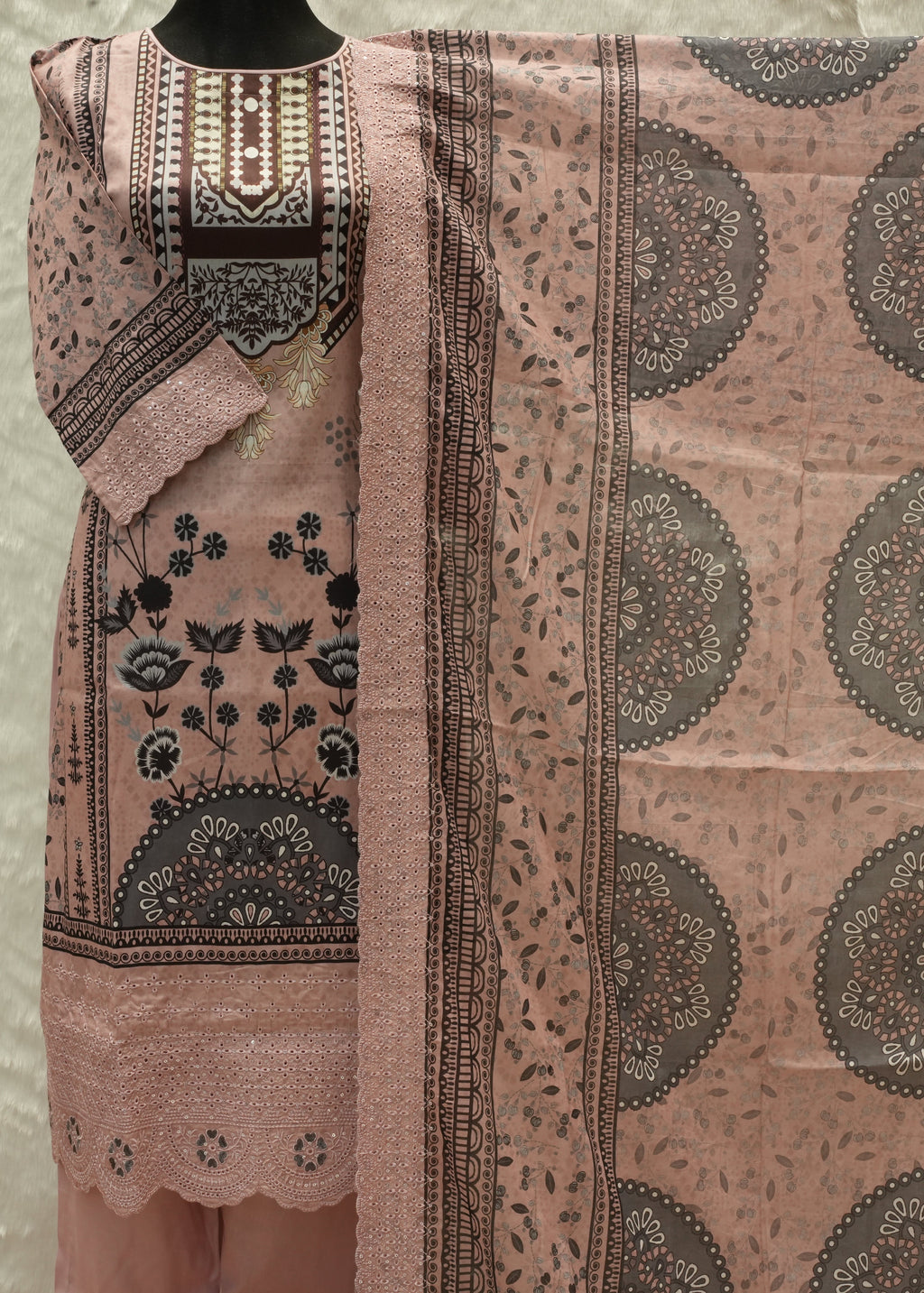 Traditional pink and black patterned fabric on a mannequin against a neutral background