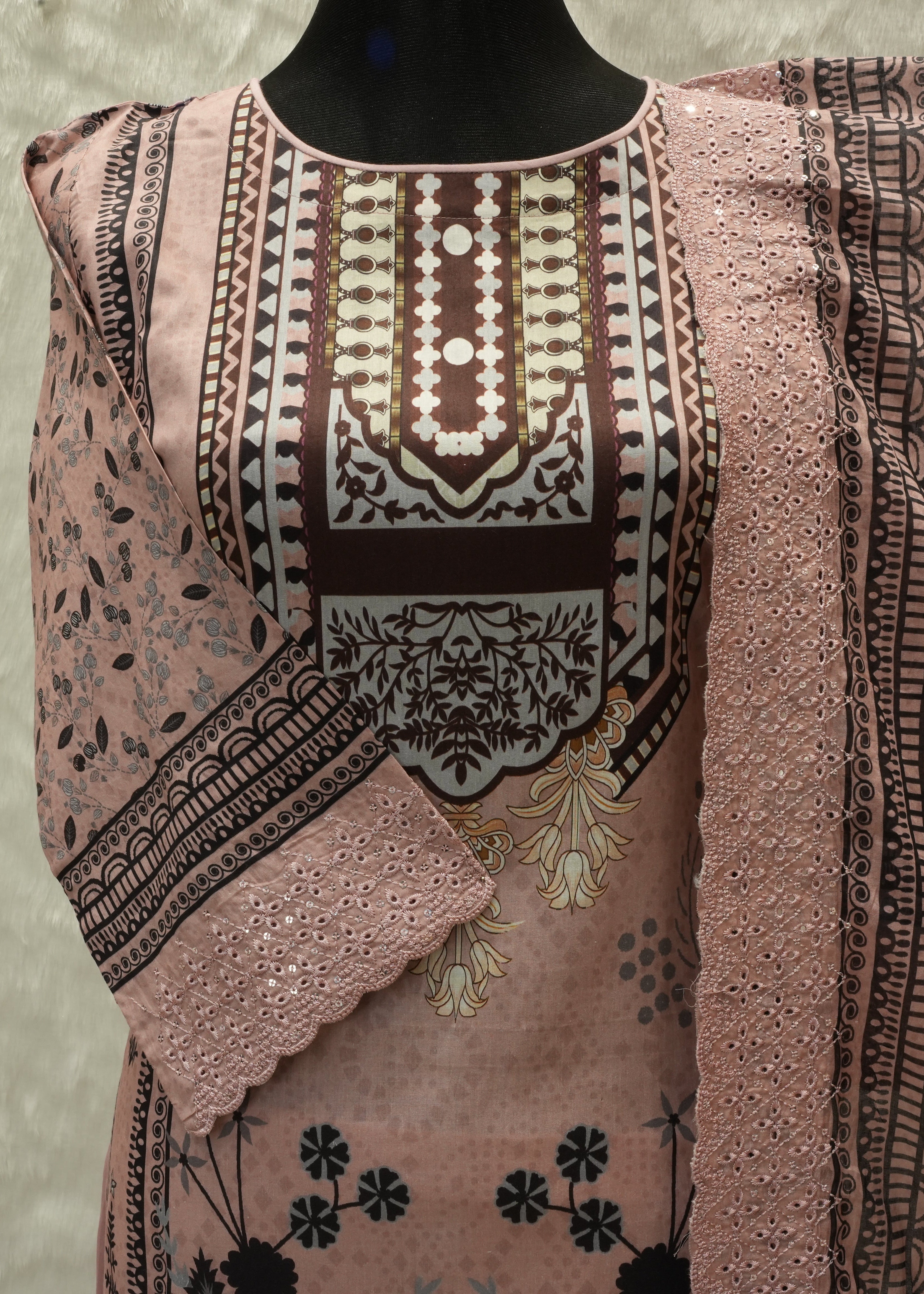 Traditional embroidered pink and black dress on a mannequin against a neutral background
