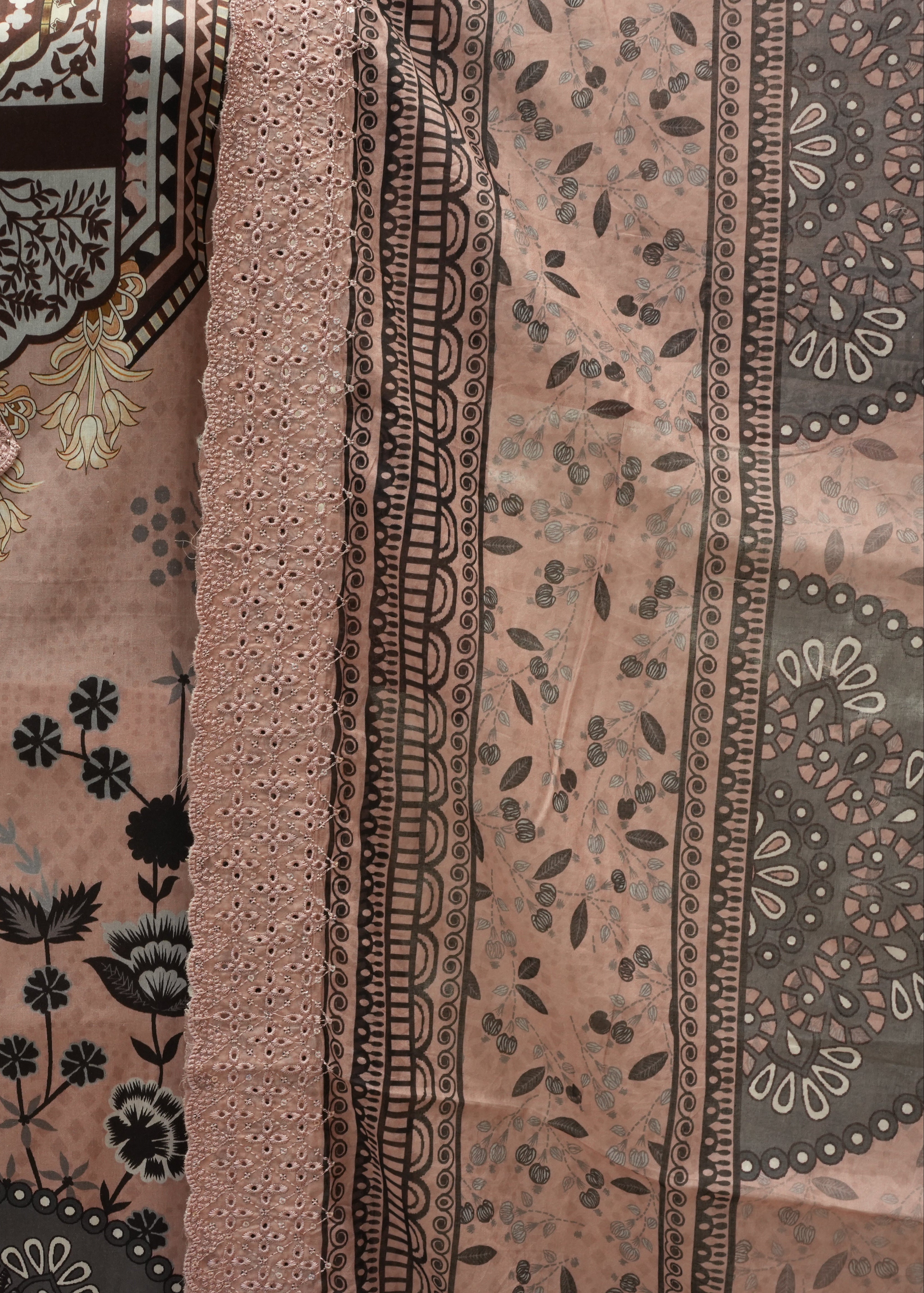 Close-up of a patterned fabric with black floral and geometric designs on a beige background.