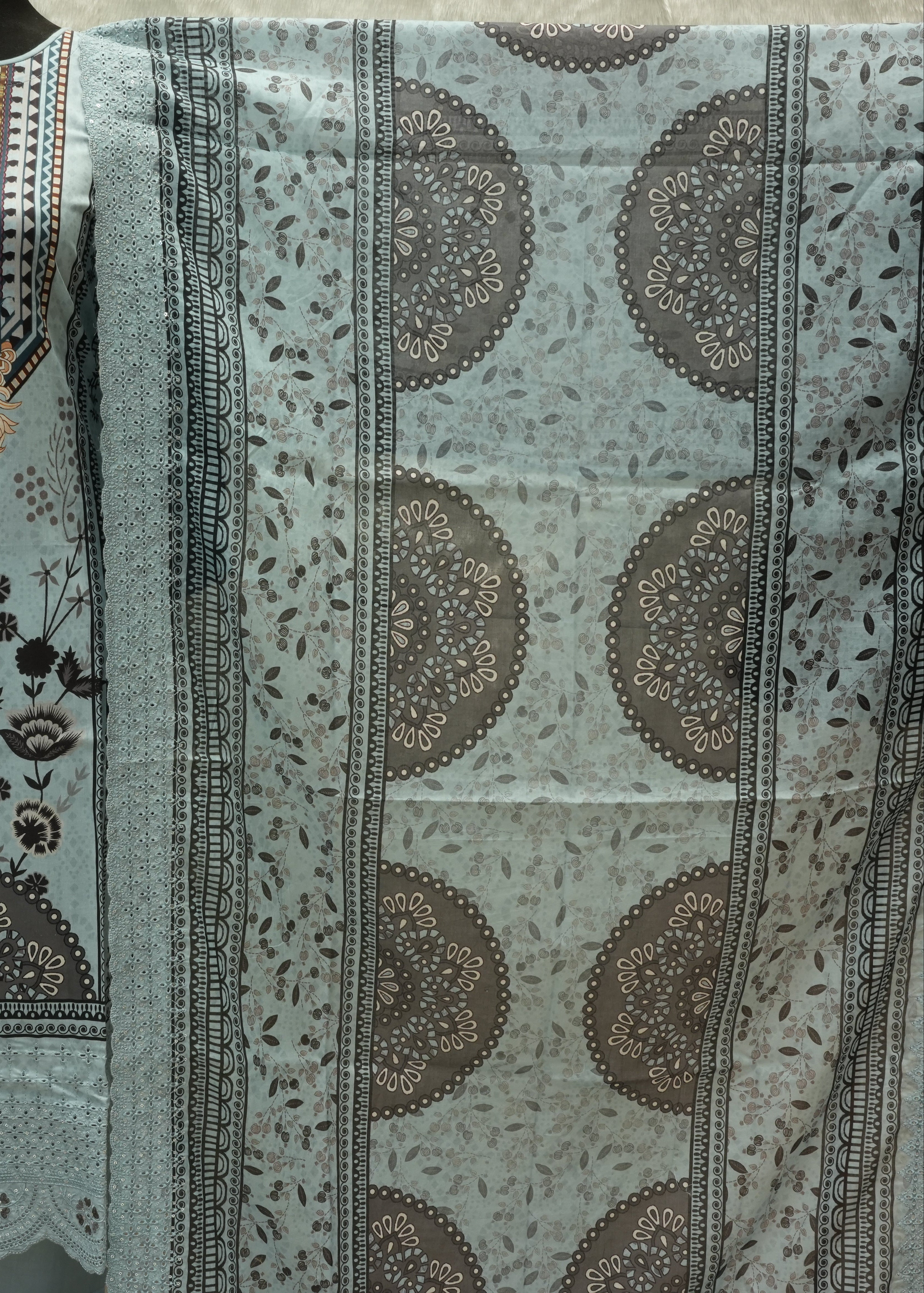 Light blue fabric with brown circular patterns on a neutral background