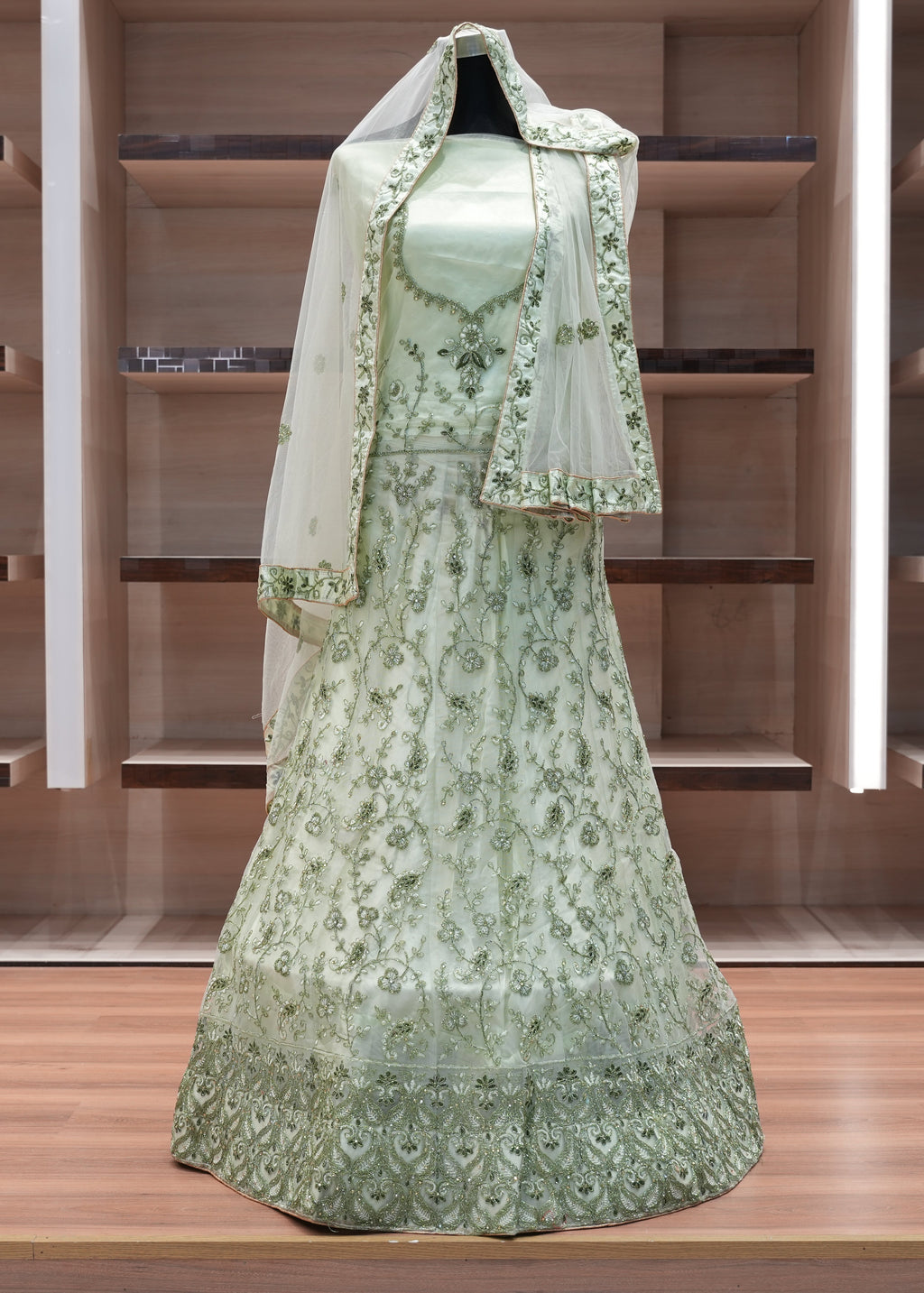 Green embroidered dress with a matching shawl on a wooden shelf.