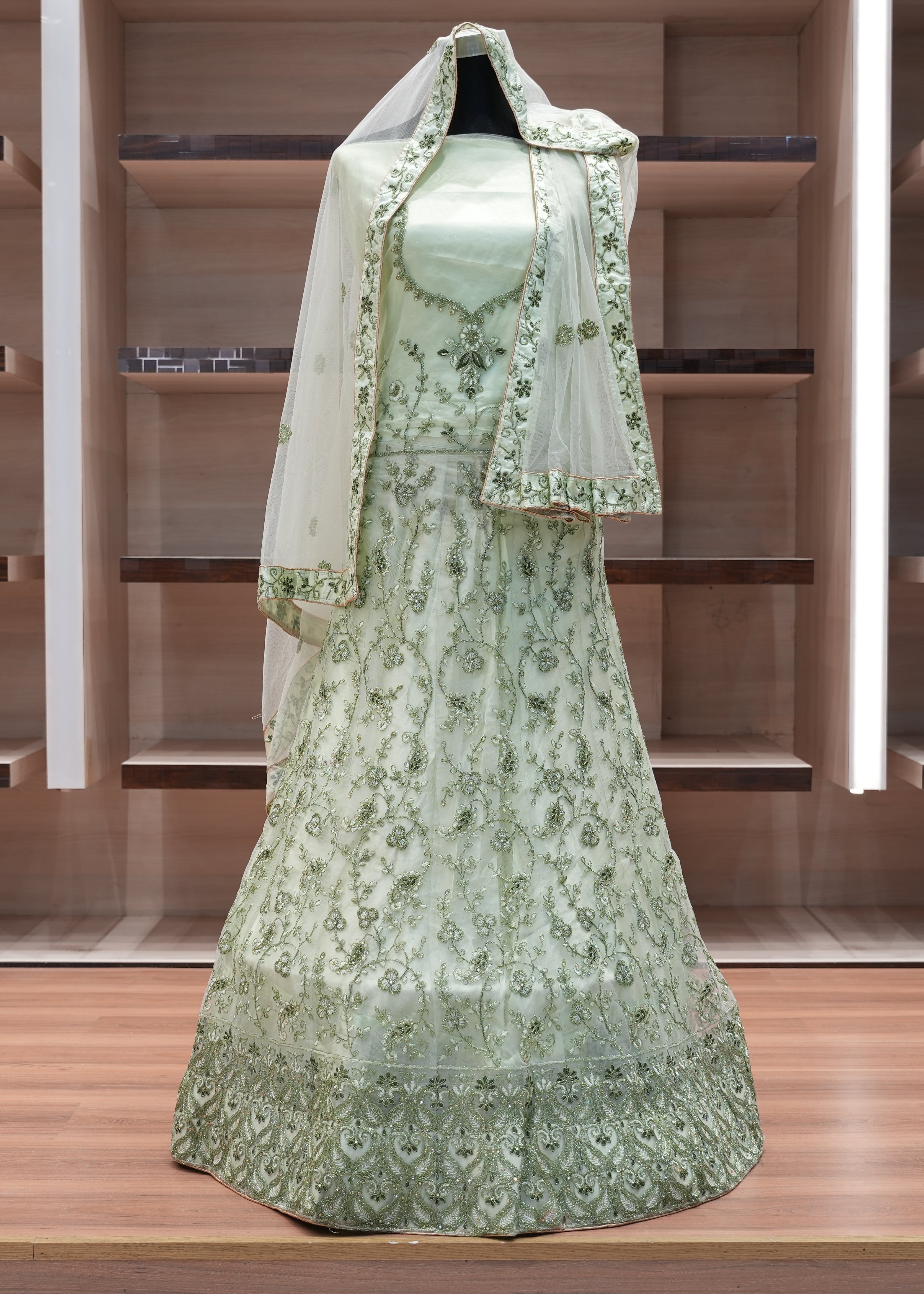Green embroidered dress with a matching shawl on a wooden shelf.
