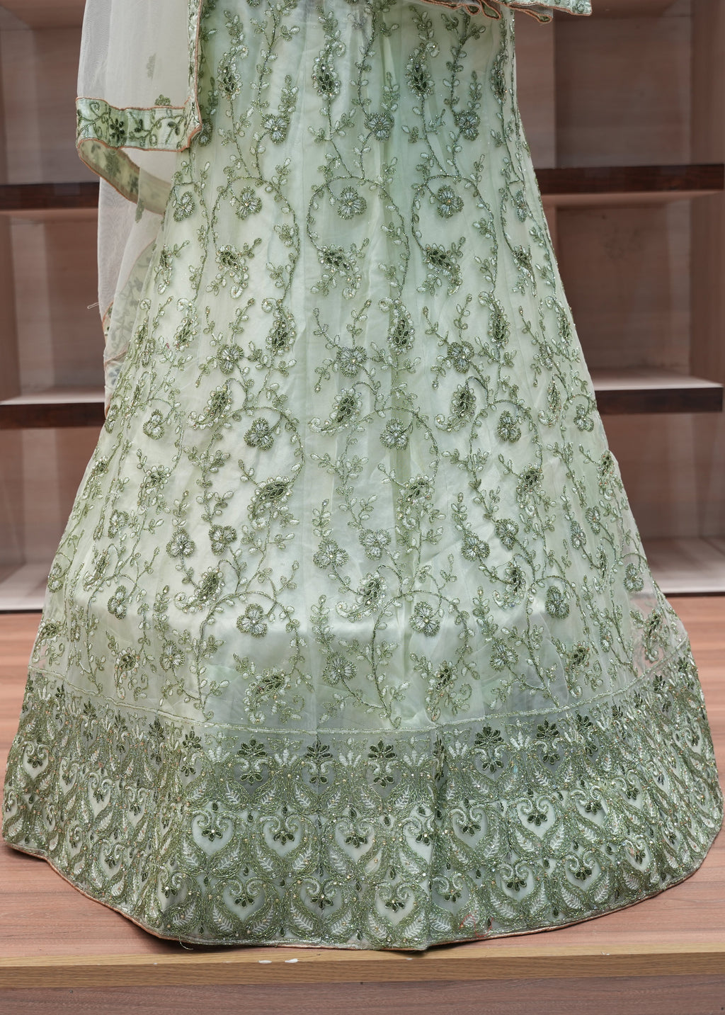 Green embroidered dress on a wooden floor with a neutral background