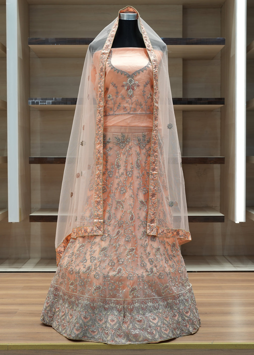 Traditional embroidered dress with a veil on a mannequin against a neutral background