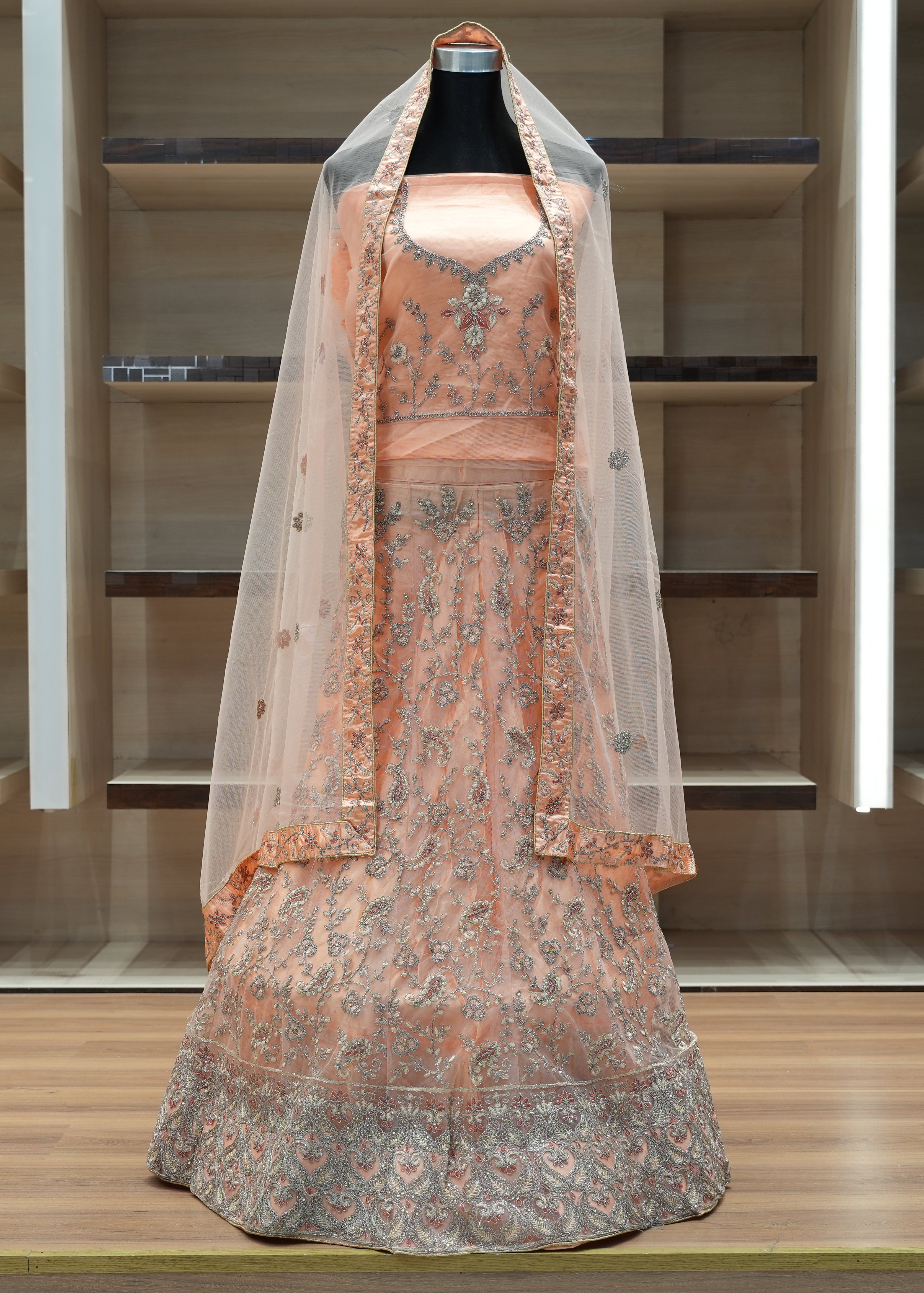 Traditional embroidered dress with a veil on a mannequin against a neutral background