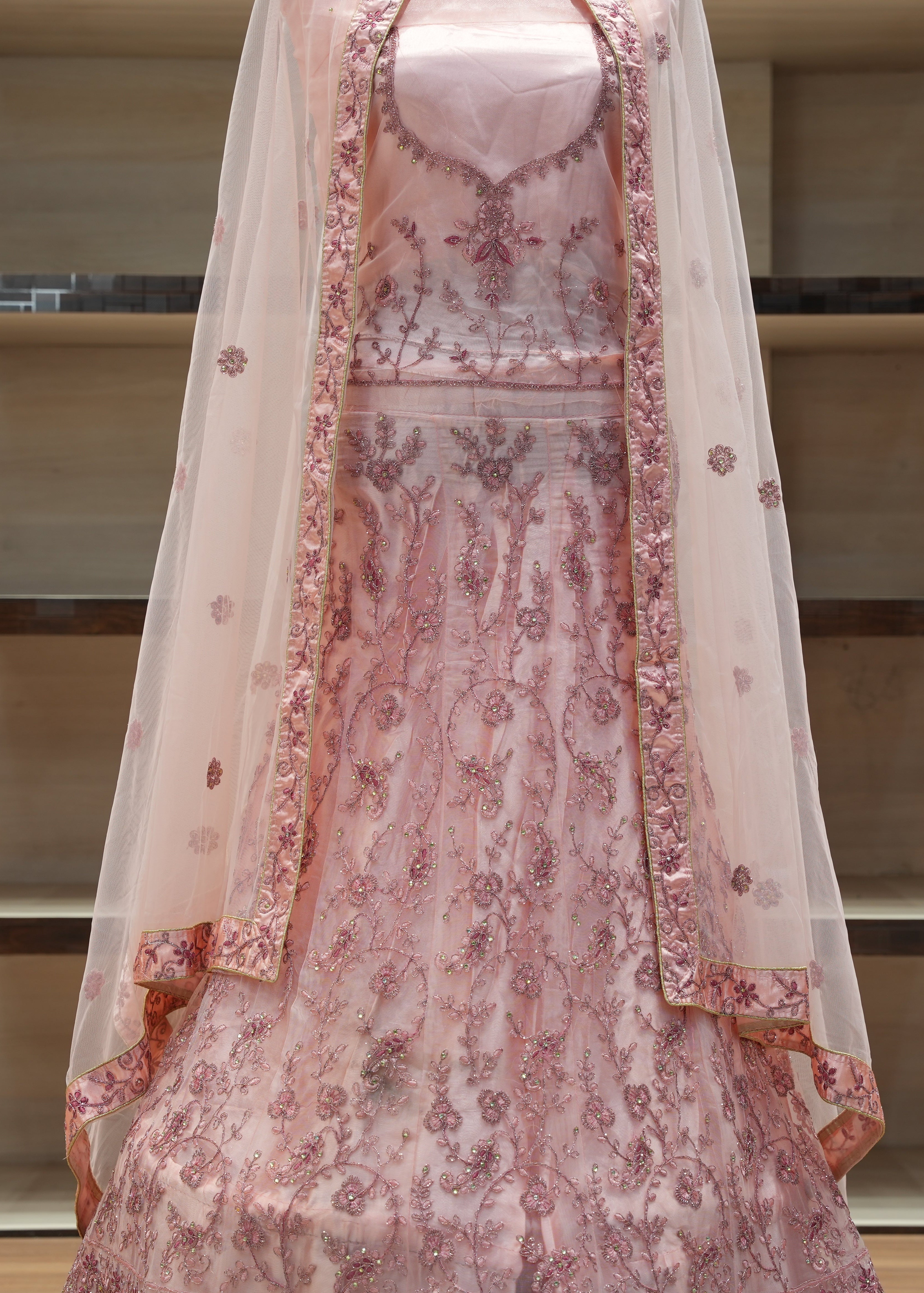 Pink embroidered traditional outfit with a sheer dupatta on a neutral background