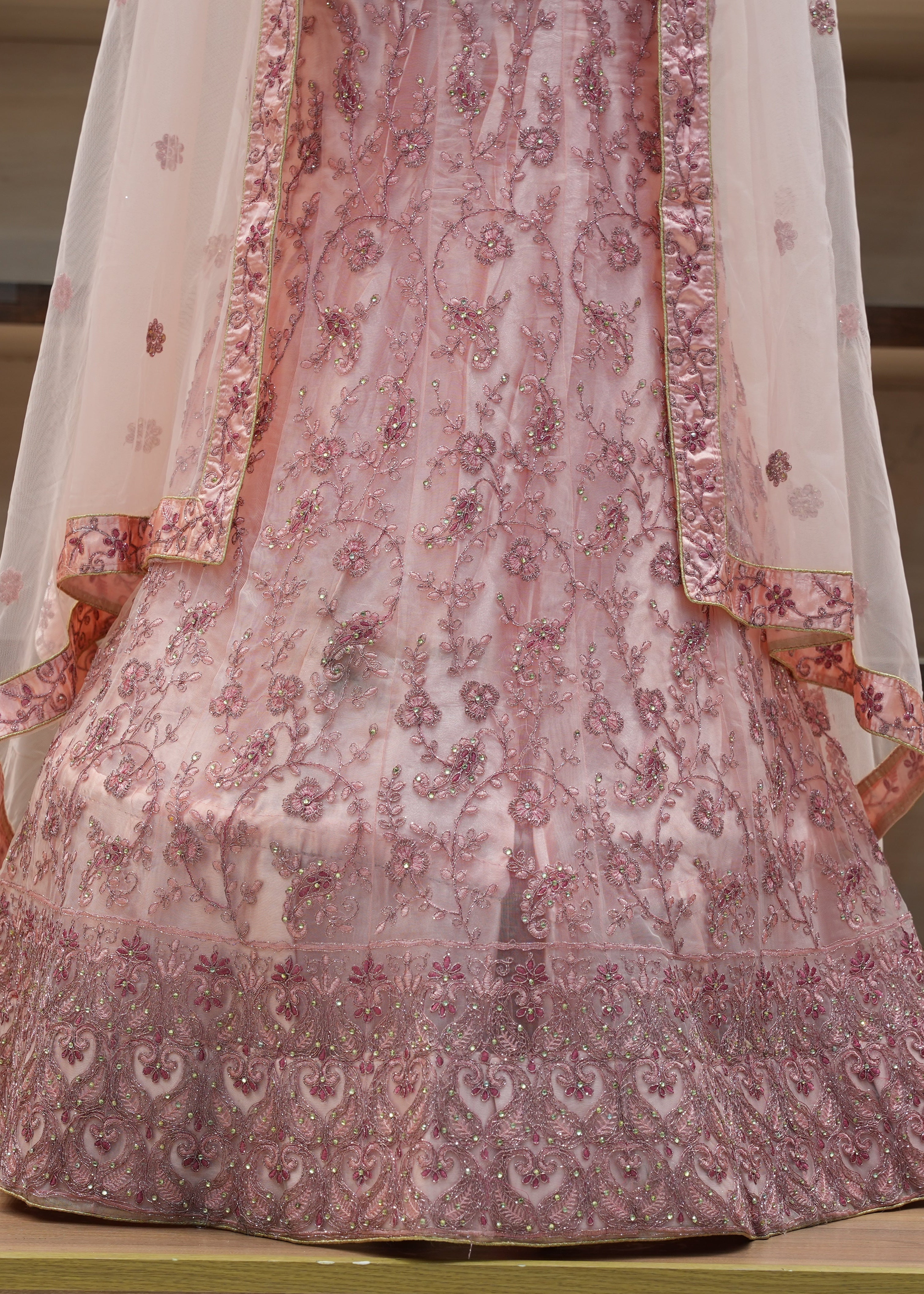 Traditional pink and white embroidered outfit on a wooden floor