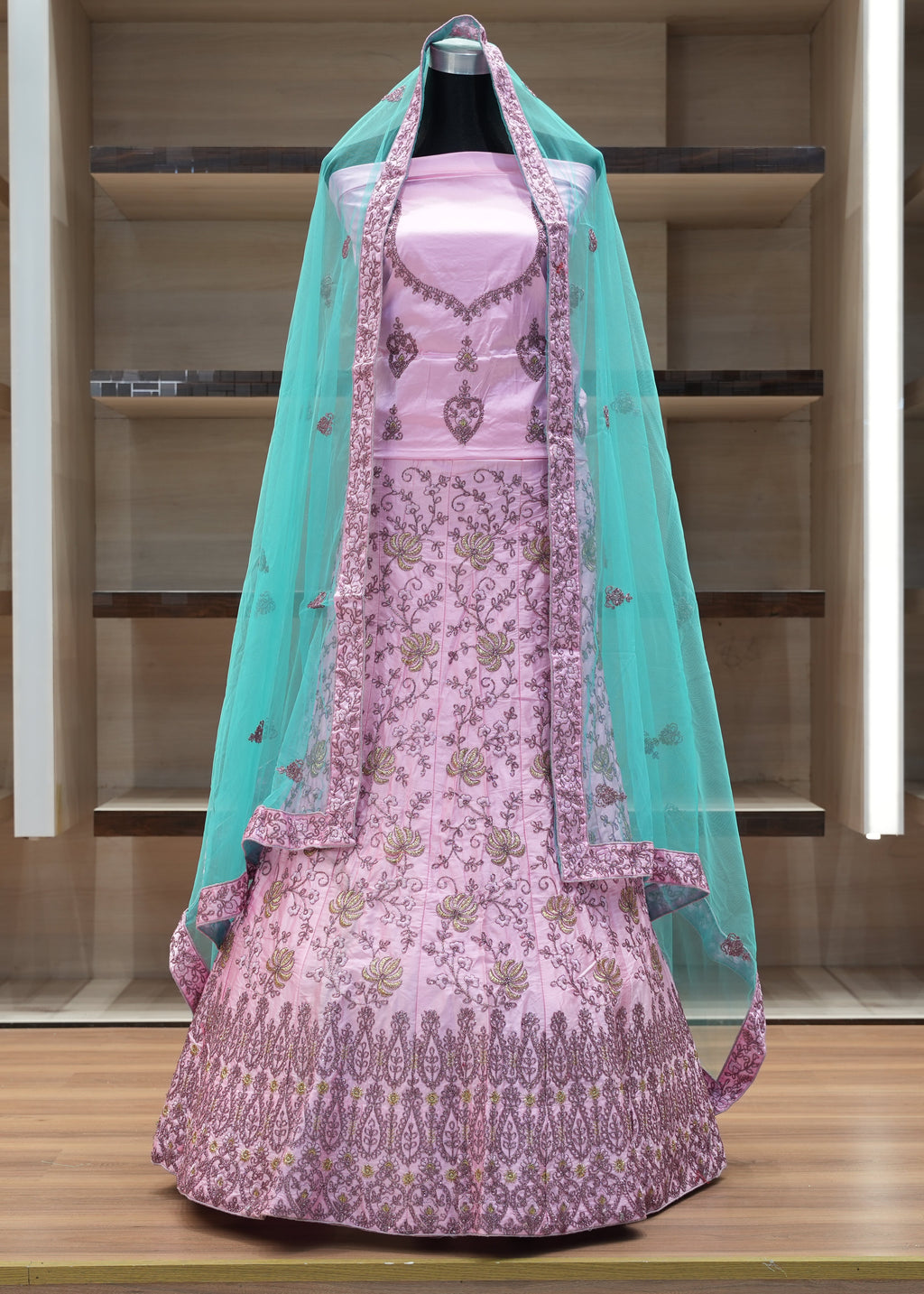 Pink embroidered dress with a green dupatta on a wooden shelf