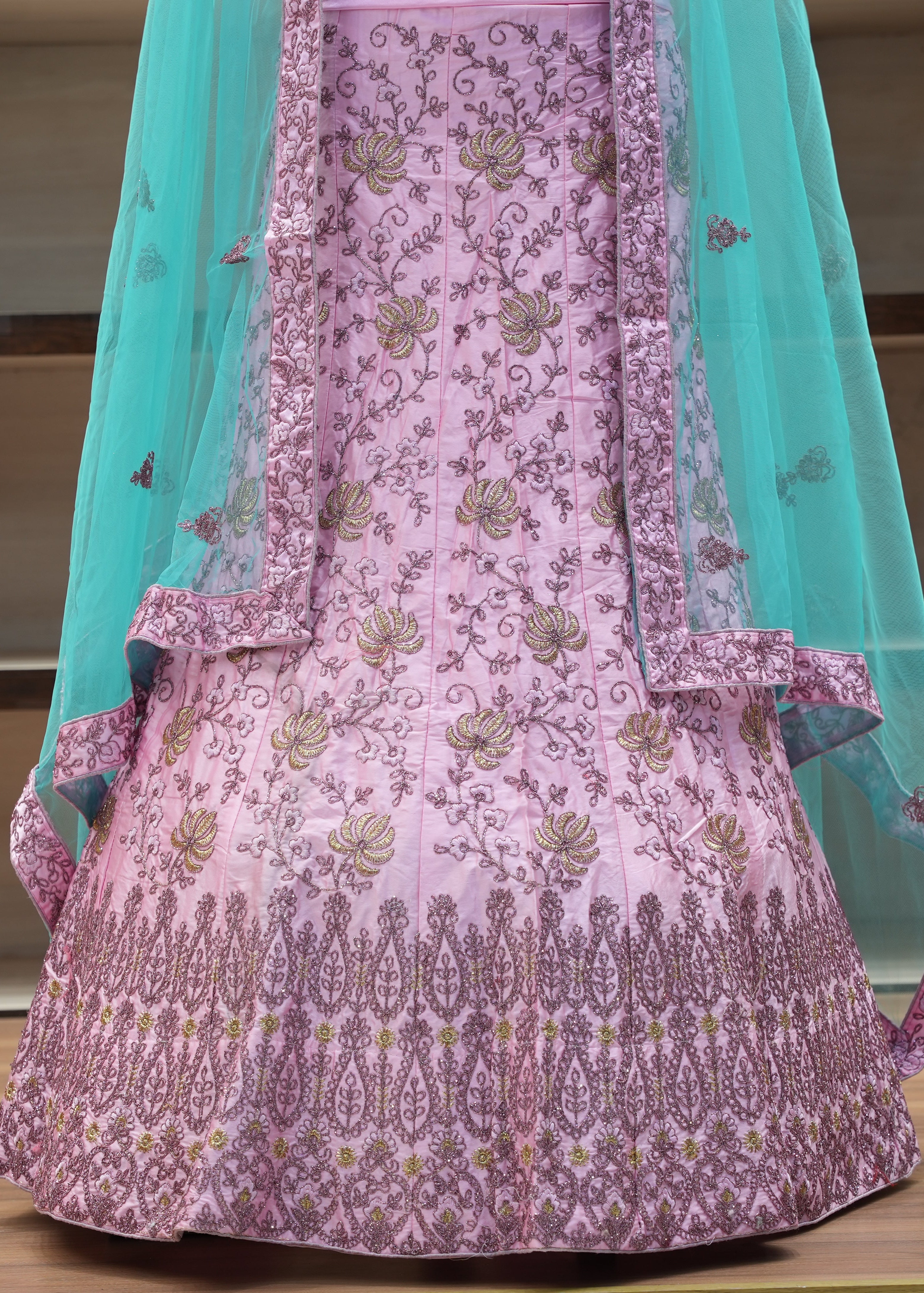 Pink embroidered traditional outfit with a turquoise dupatta on a wooden surface.