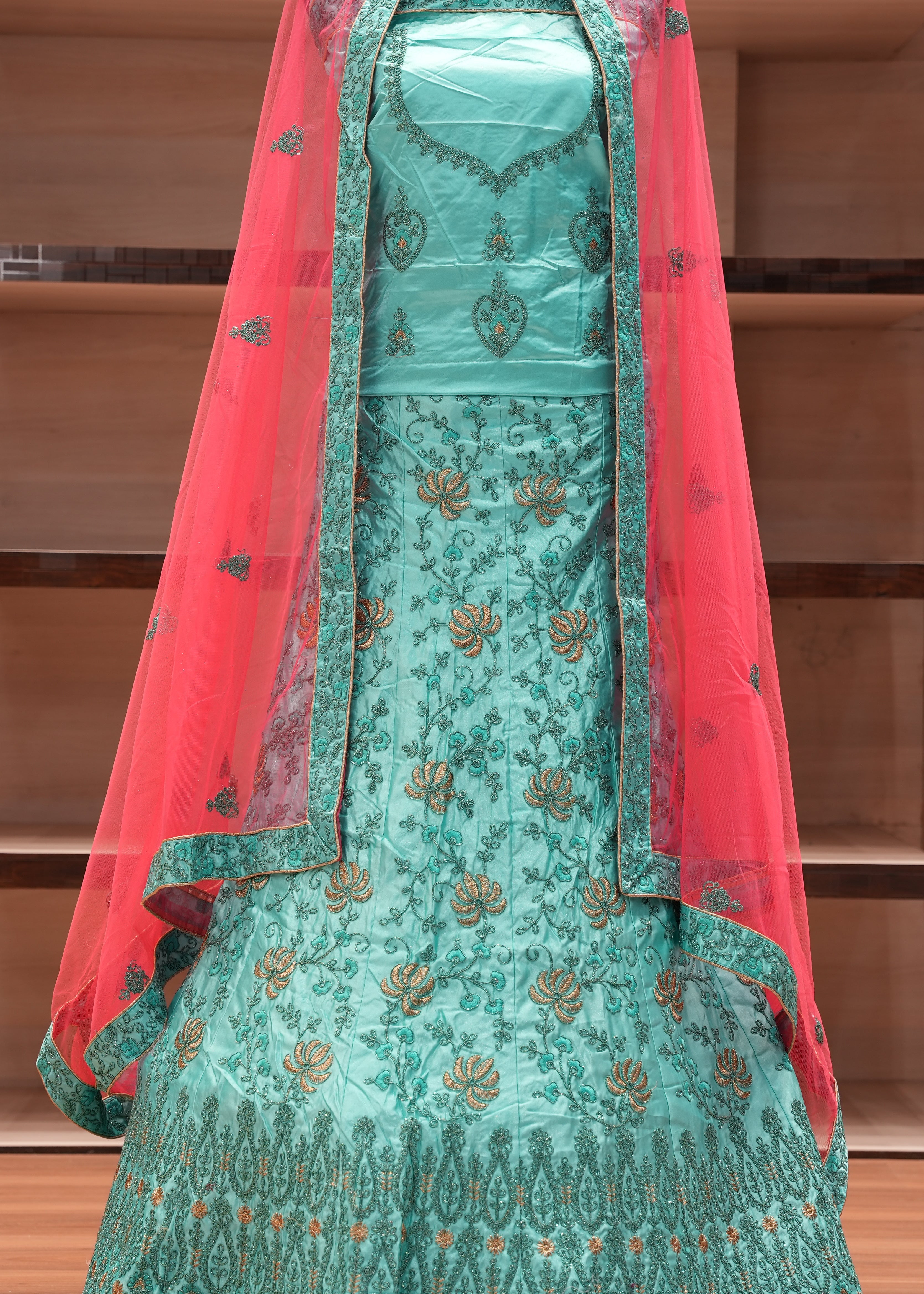 Traditional turquoise embroidered dress with a red dupatta on a wooden background