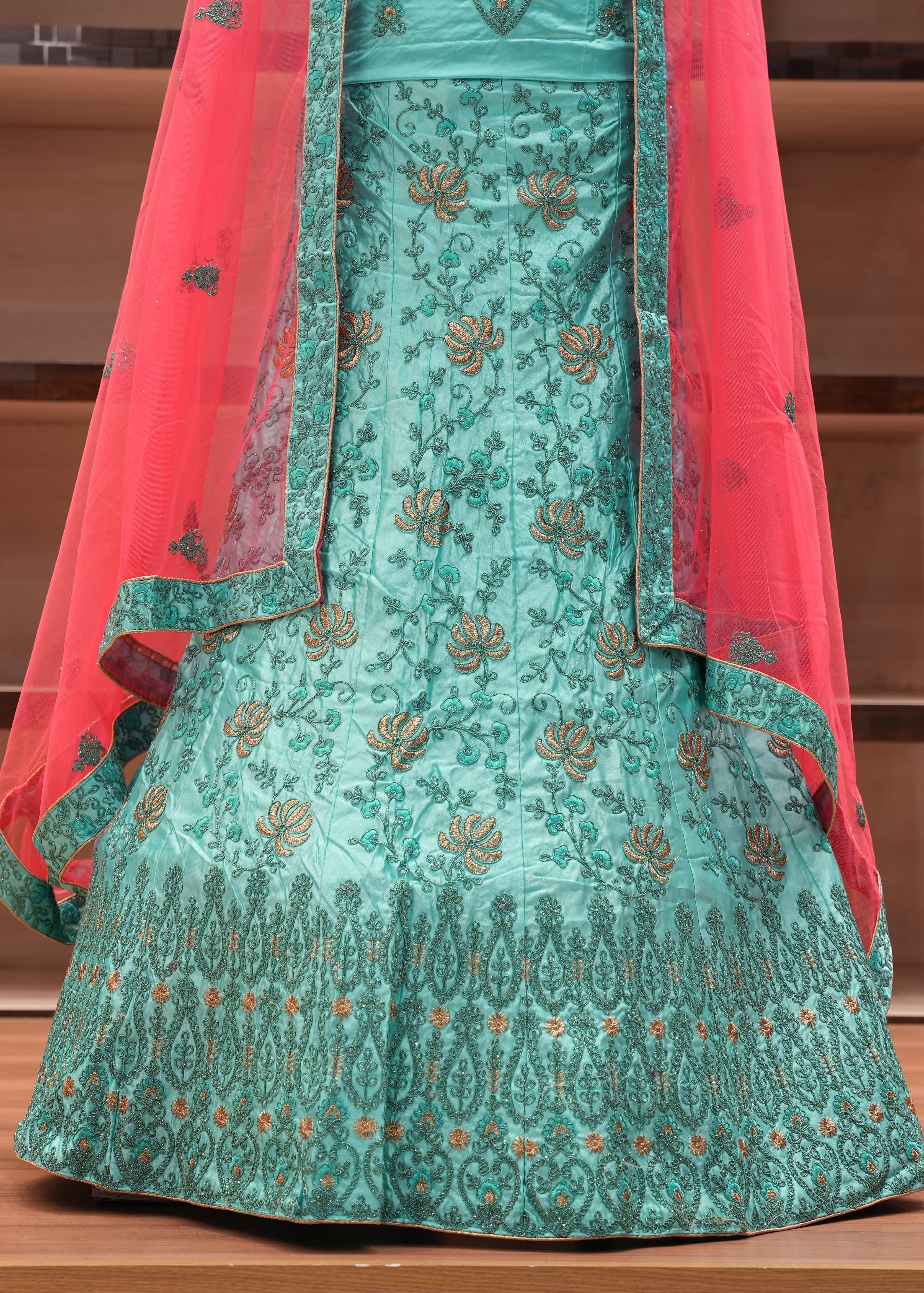 Green embroidered traditional outfit with red dupatta on a wooden surface