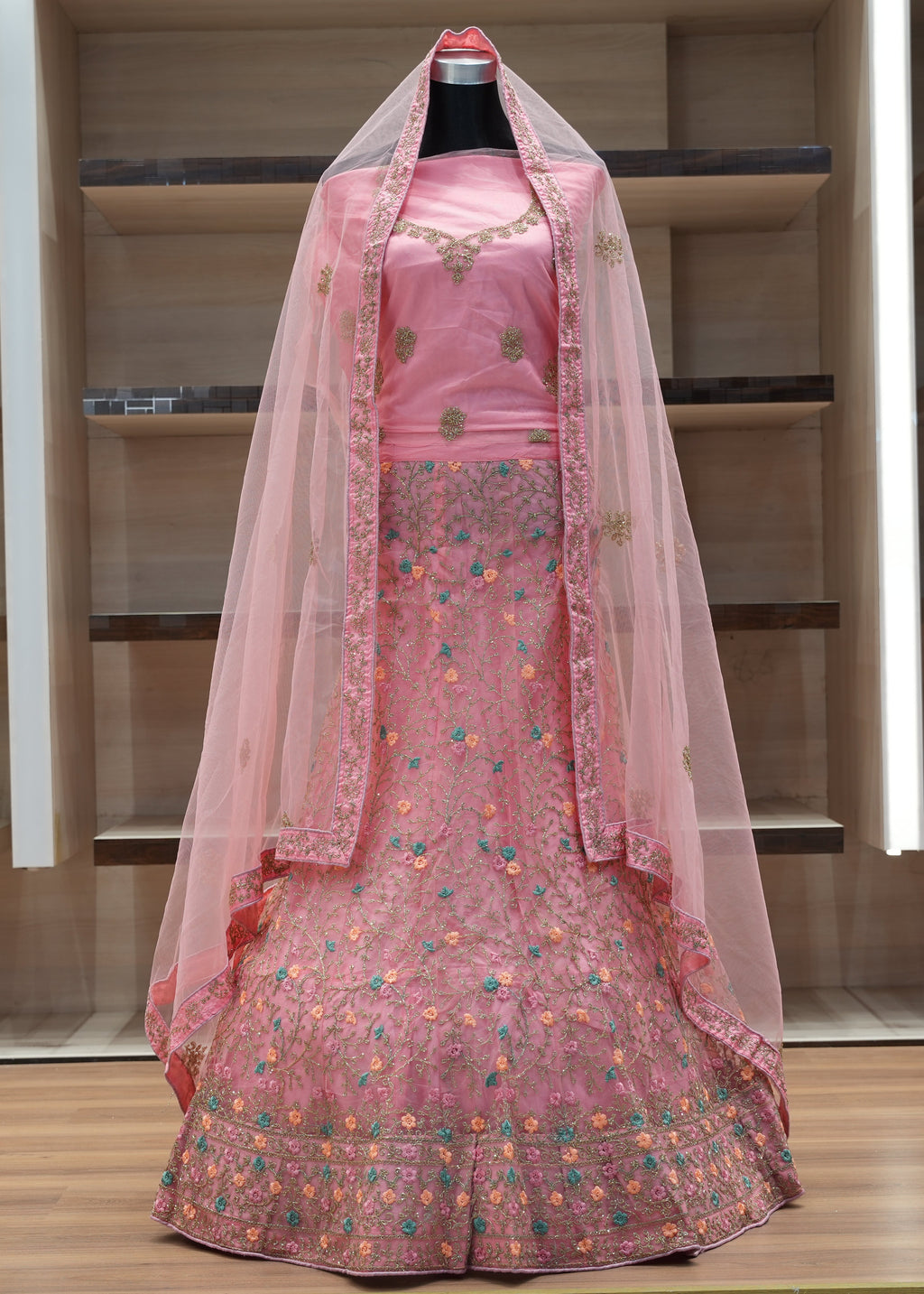 Pink embroidered traditional outfit with a sheer dupatta on a mannequin against a neutral background