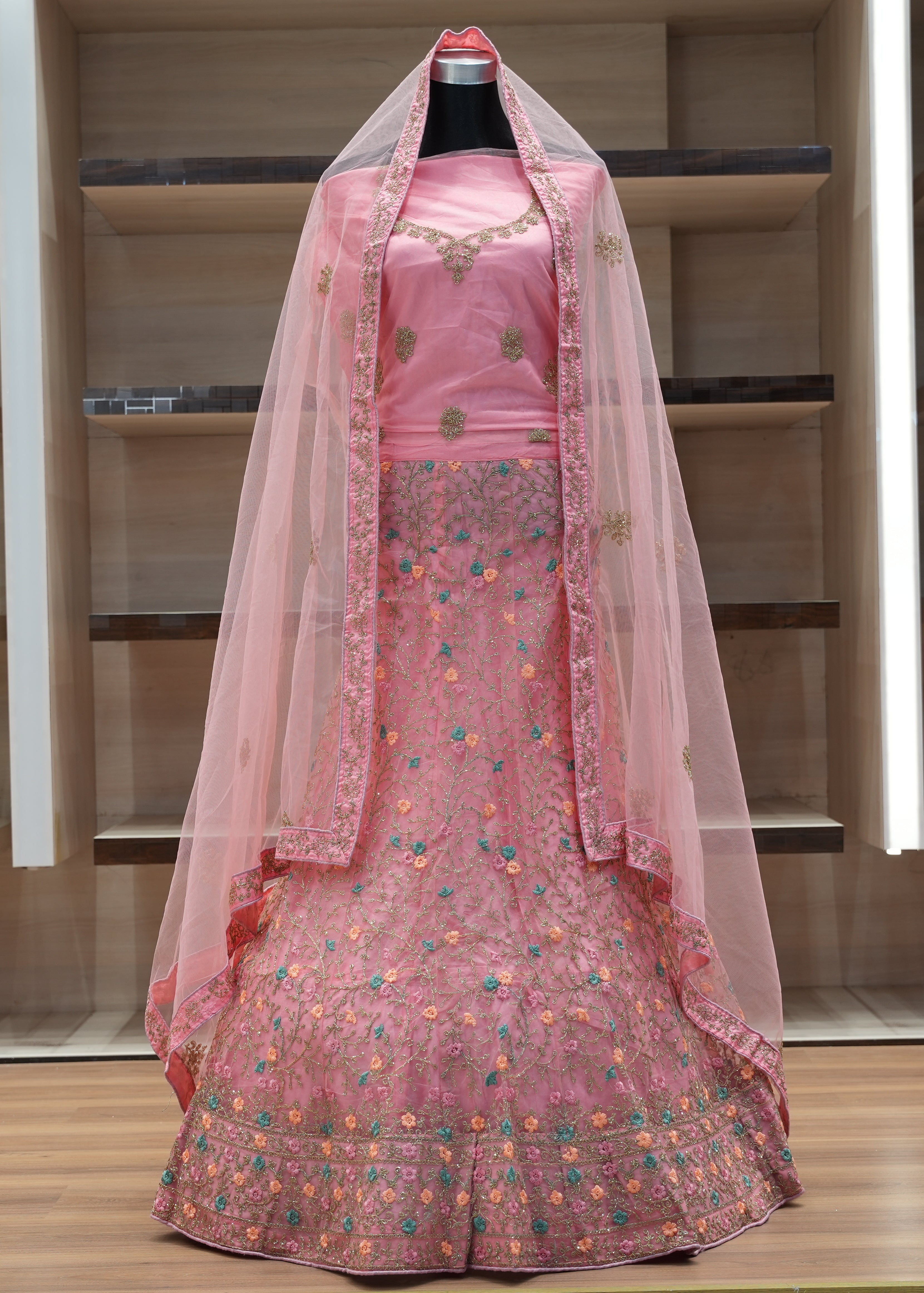 Pink embroidered traditional outfit with a sheer dupatta on a mannequin against a neutral background