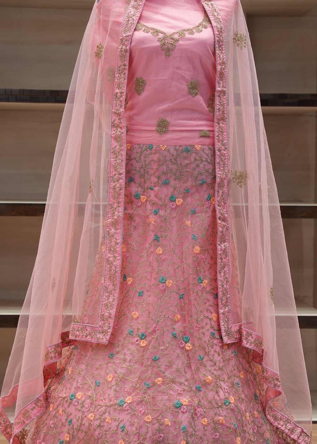 Pink embroidered traditional outfit with a sheer dupatta on a neutral background