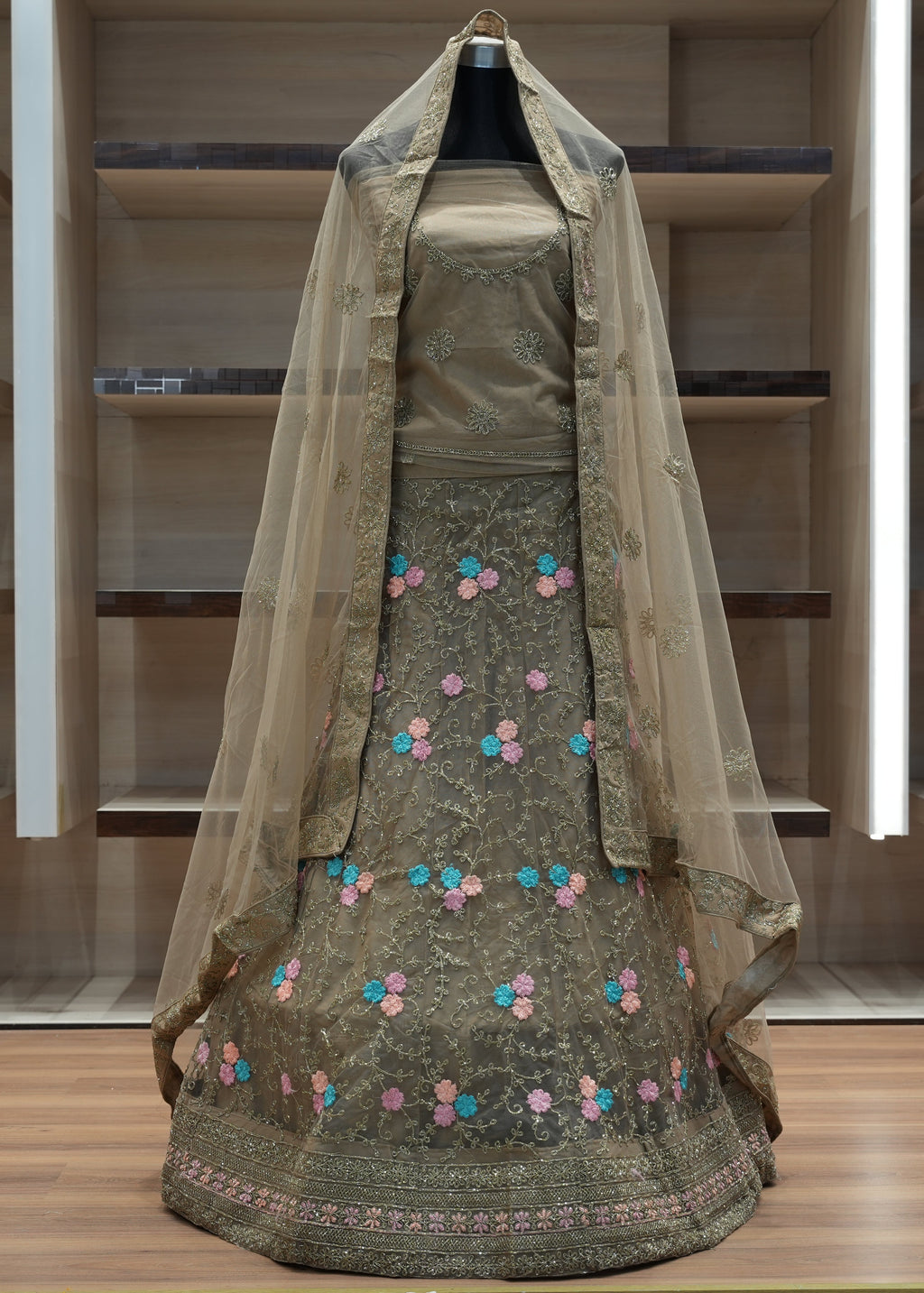 Traditional green embroidered dress with a sheer dupatta on a wooden floor.