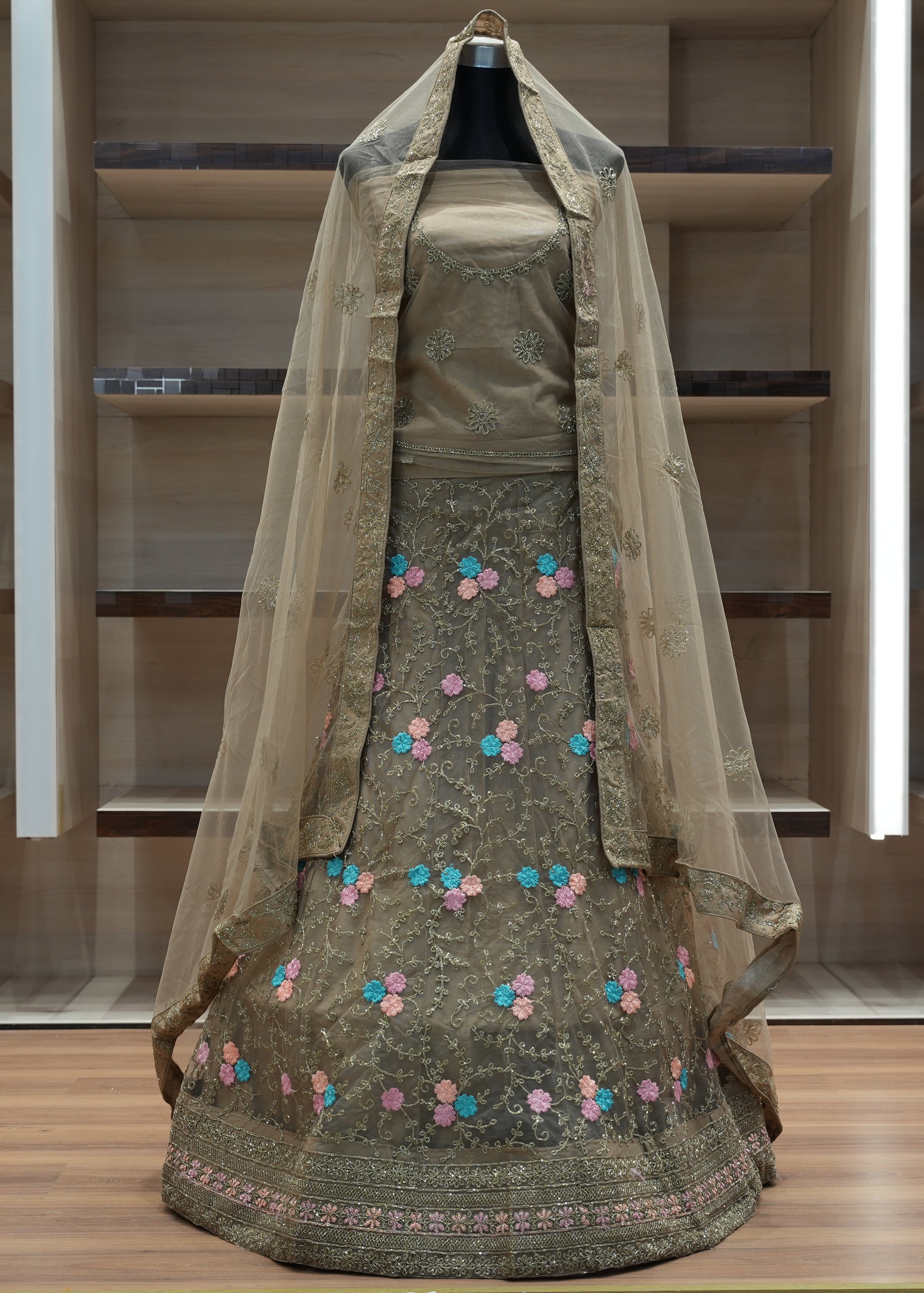 Traditional green embroidered dress with a sheer dupatta on a wooden floor.