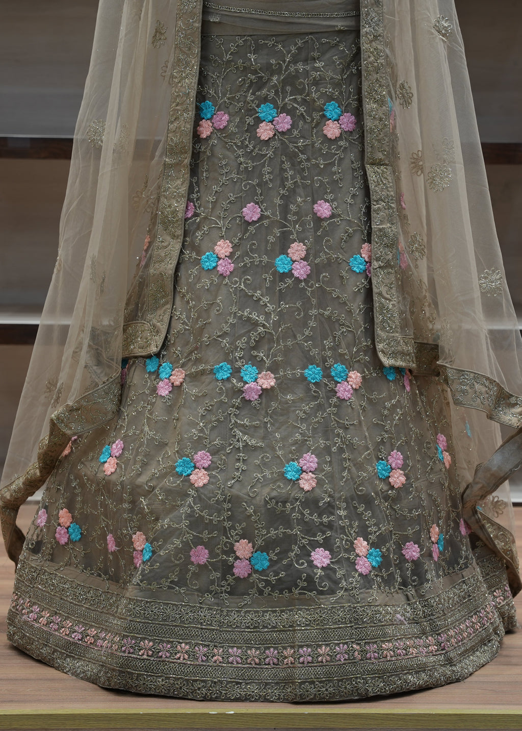 Traditional embroidered outfit with a sheer dupatta on a wooden surface