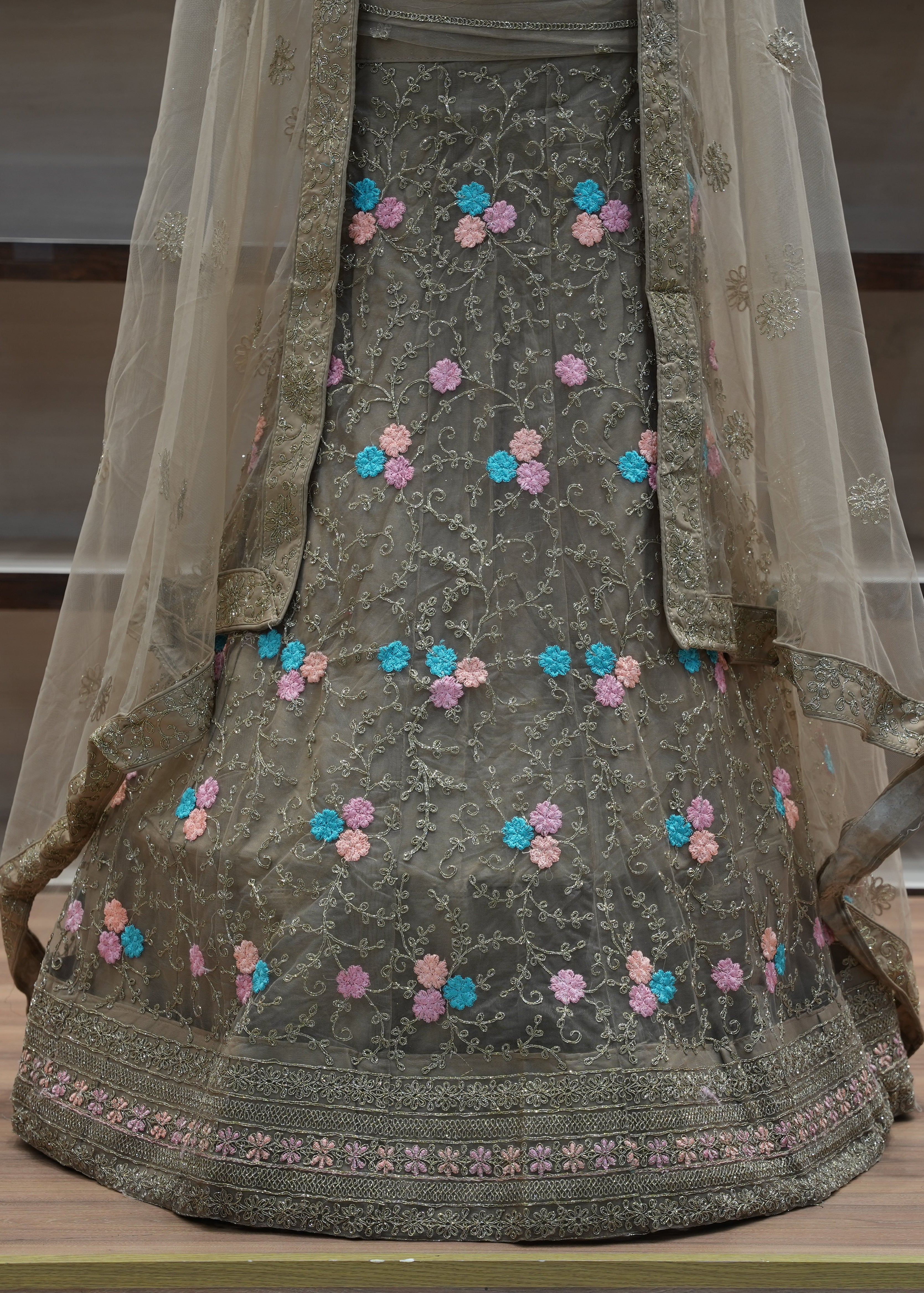 Traditional embroidered outfit with a sheer dupatta on a wooden surface