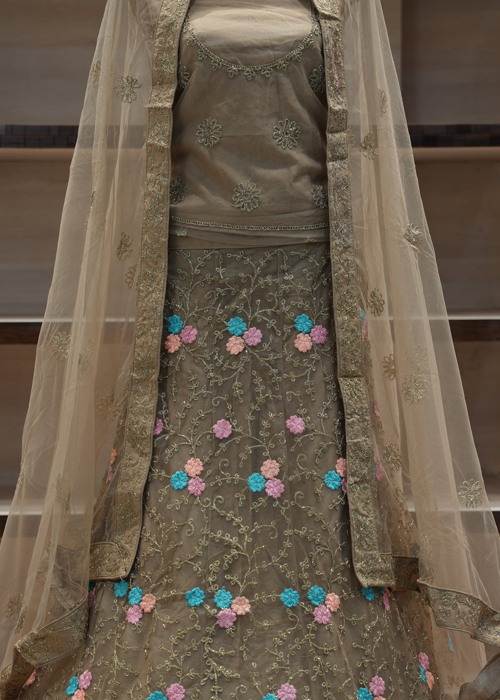 Traditional embroidered outfit with a sheer dupatta on a neutral background