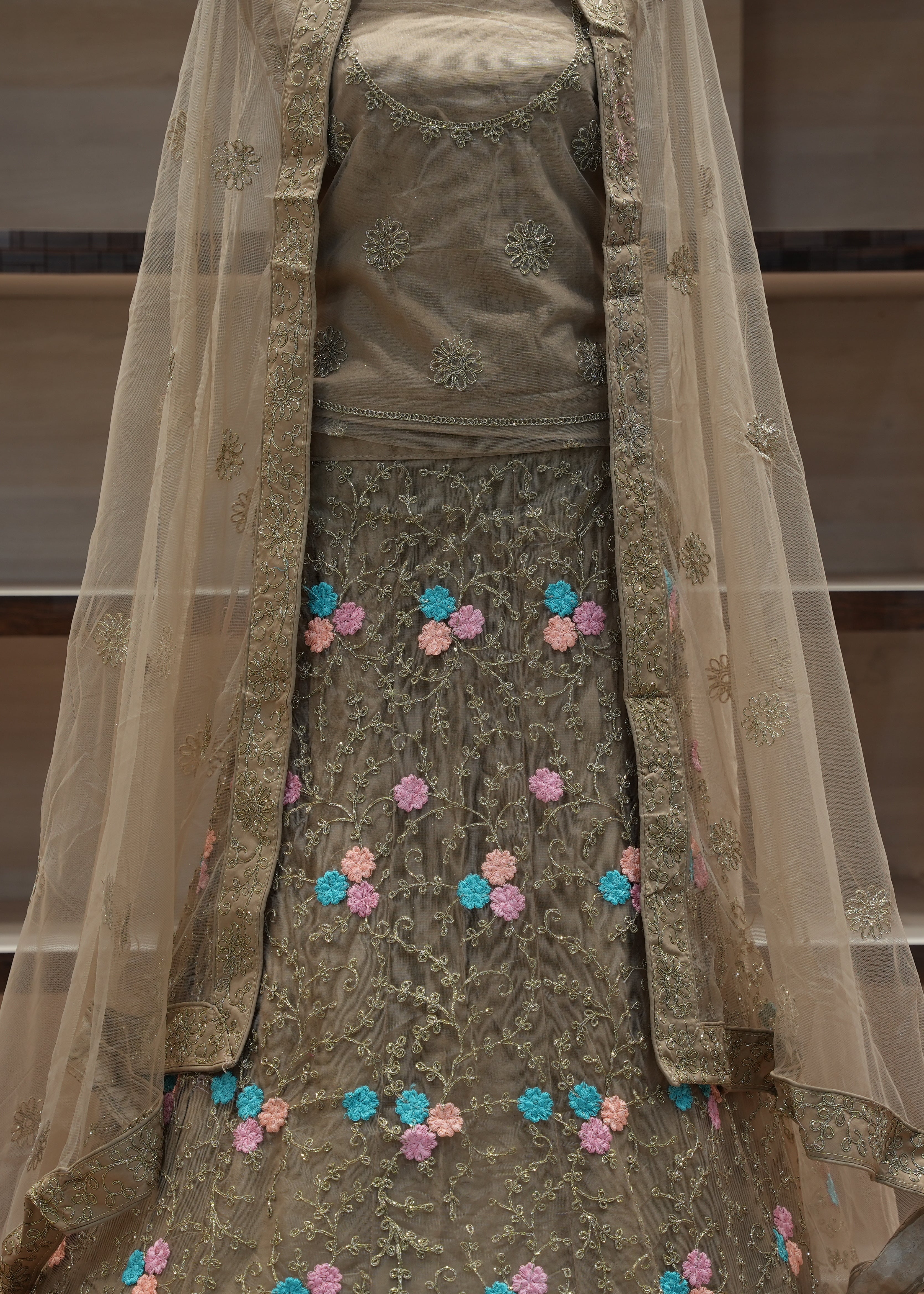 Traditional embroidered outfit with a sheer dupatta on a neutral background