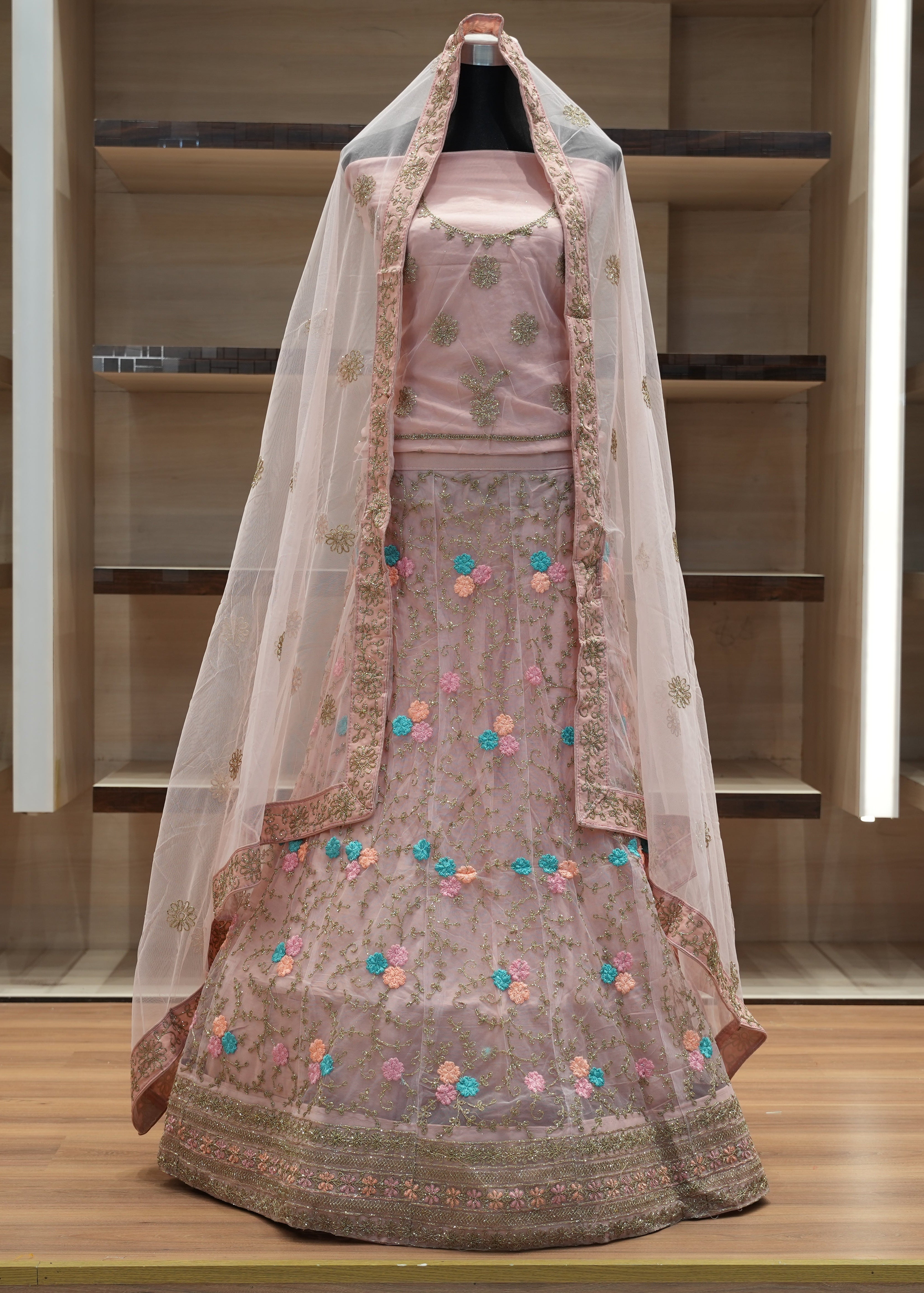 Traditional embroidered outfit with a sheer dupatta on a wooden shelf.