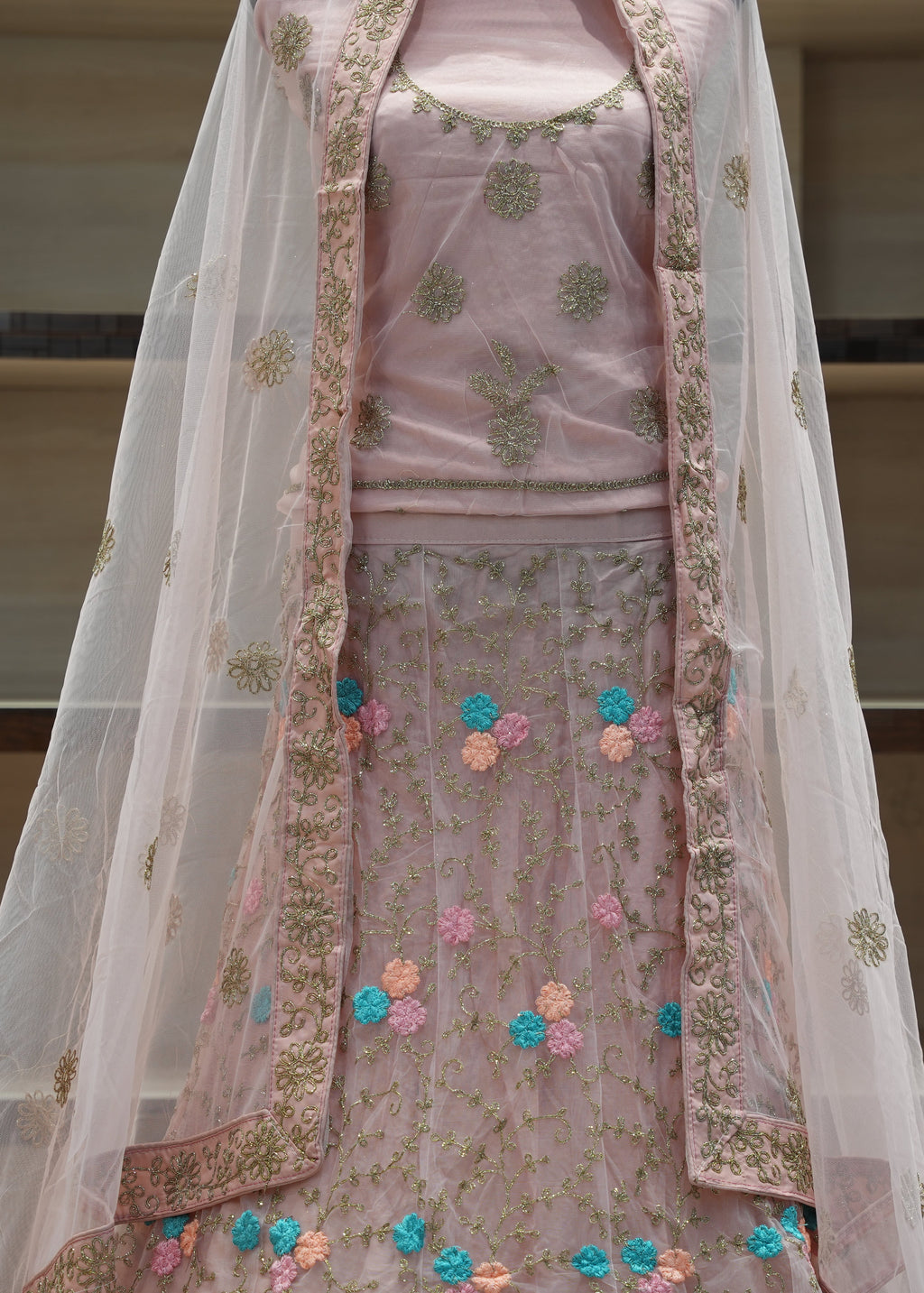 Traditional pink embroidered outfit with a sheer dupatta on a neutral background