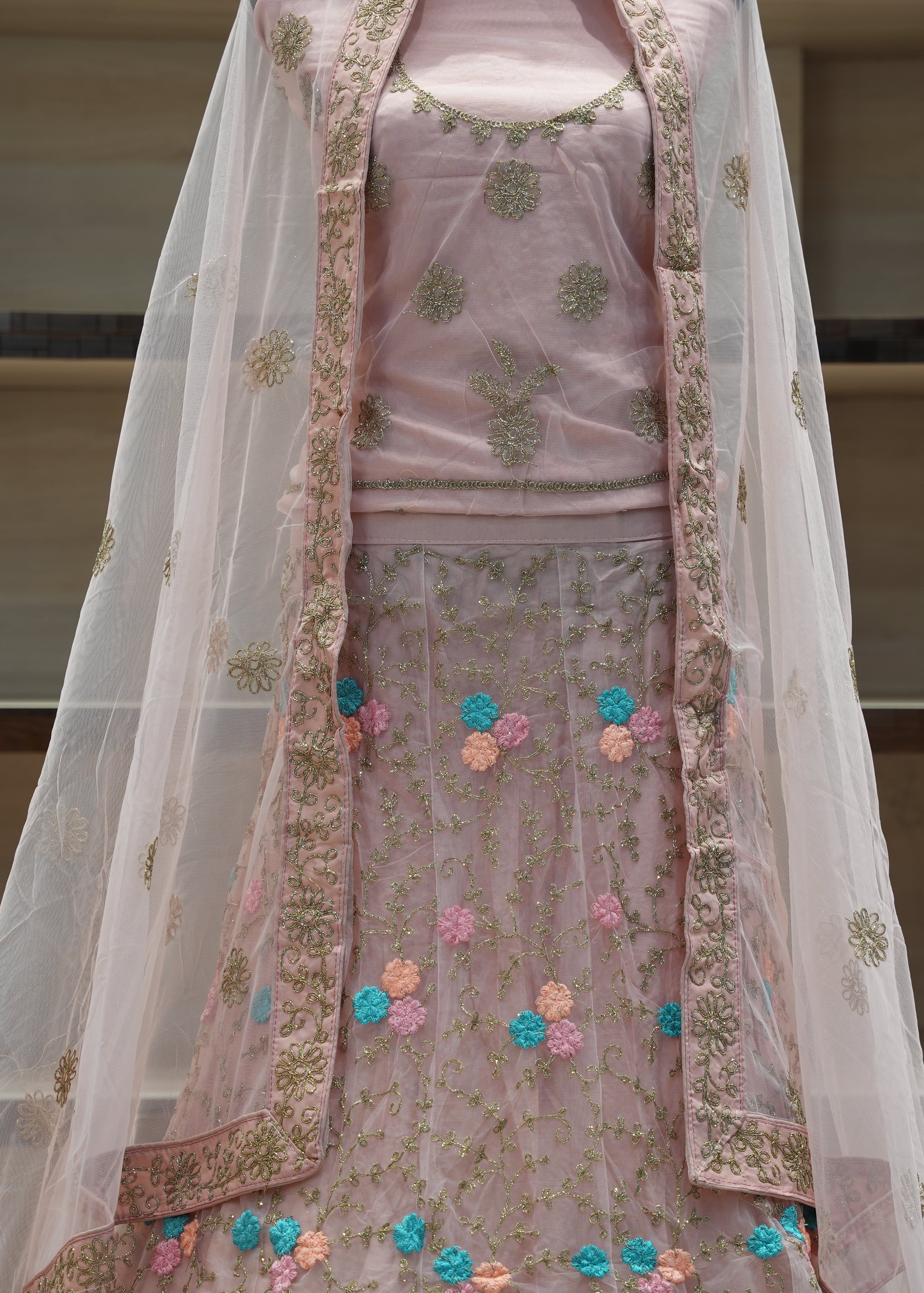 Traditional pink embroidered outfit with a sheer dupatta on a neutral background