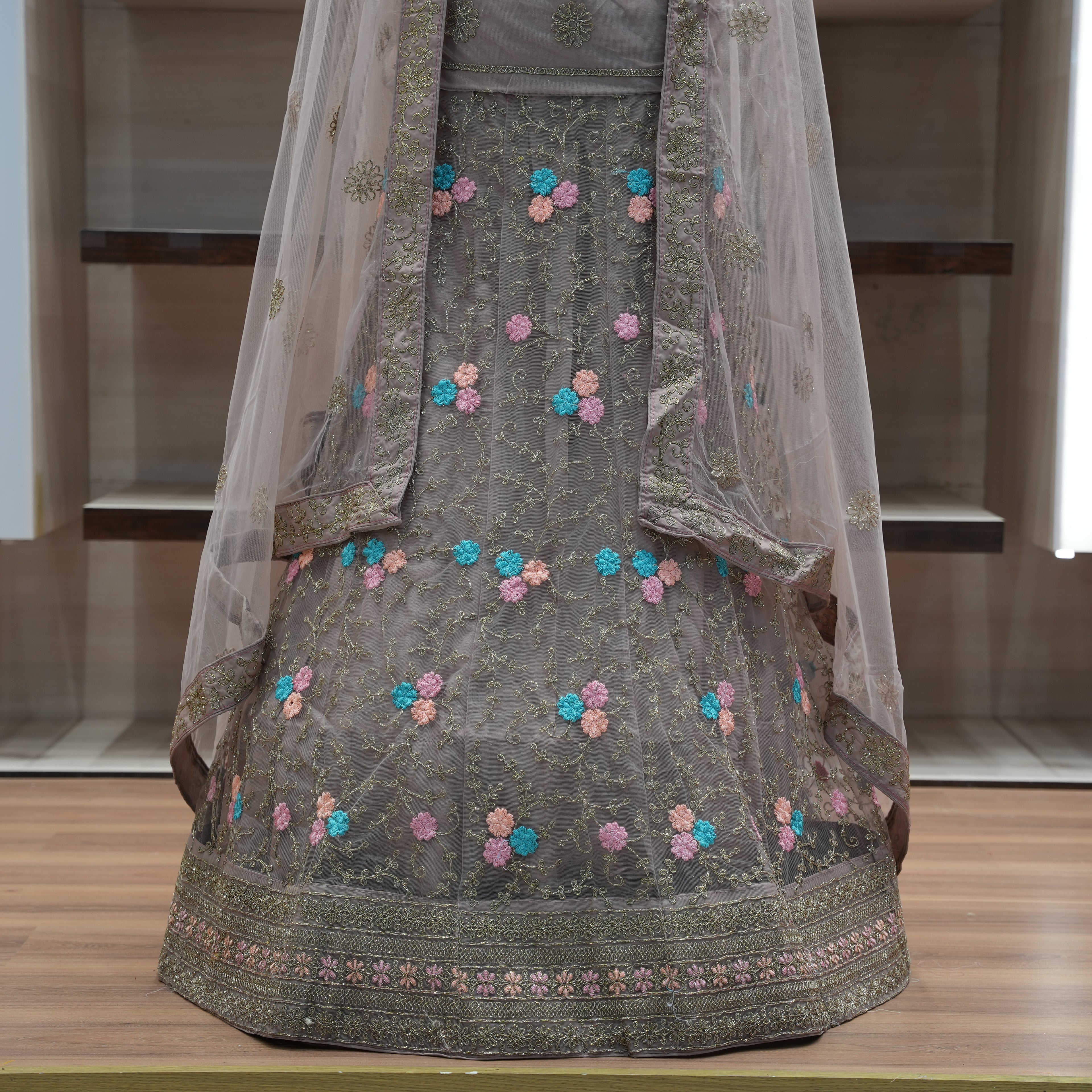 Traditional embroidered outfit with a sheer dupatta on a wooden surface