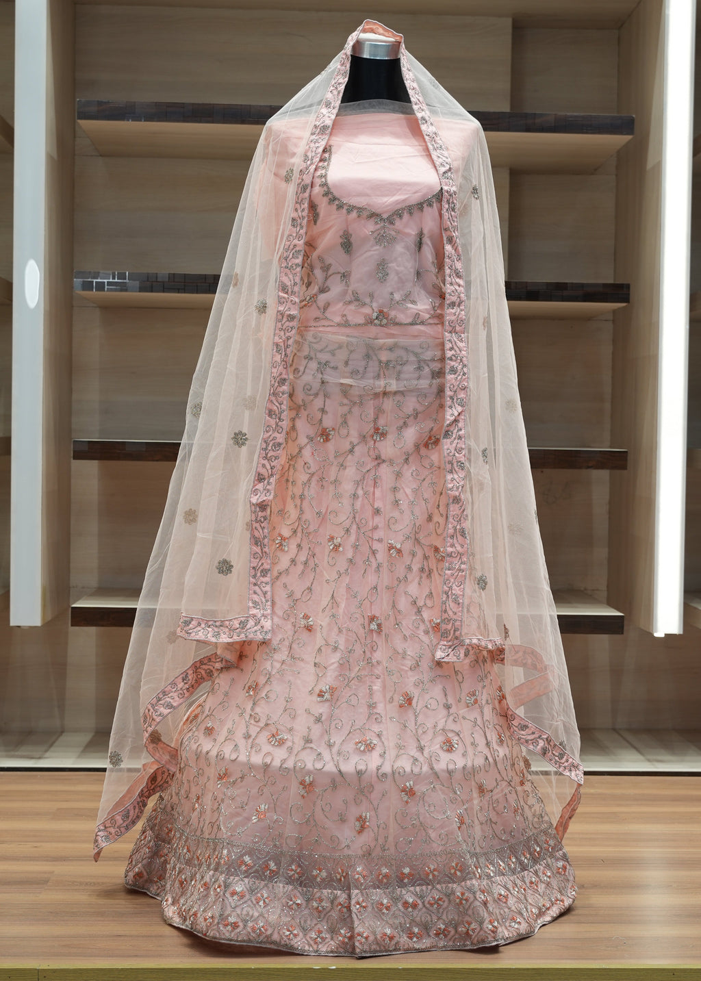 Traditional pink embroidered dress with a sheer dupatta on a mannequin against a neutral background