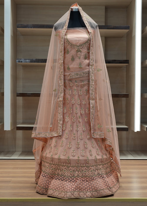 Traditional embroidered pink outfit with a sheer dupatta on a wooden floor.