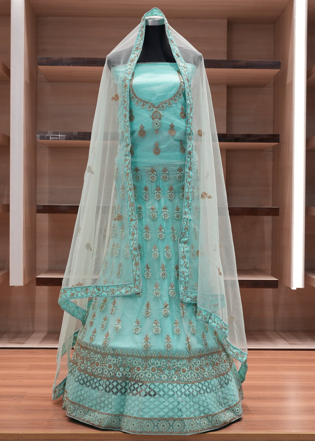 Turquoise embroidered traditional outfit with a veil on a wooden shelf.