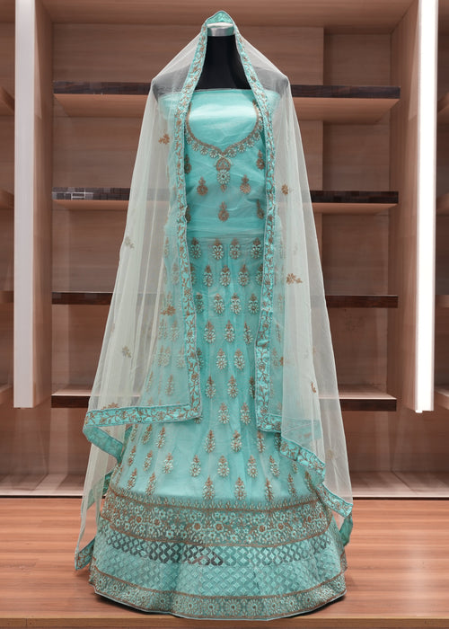 Turquoise embroidered traditional outfit with a veil on a wooden shelf.