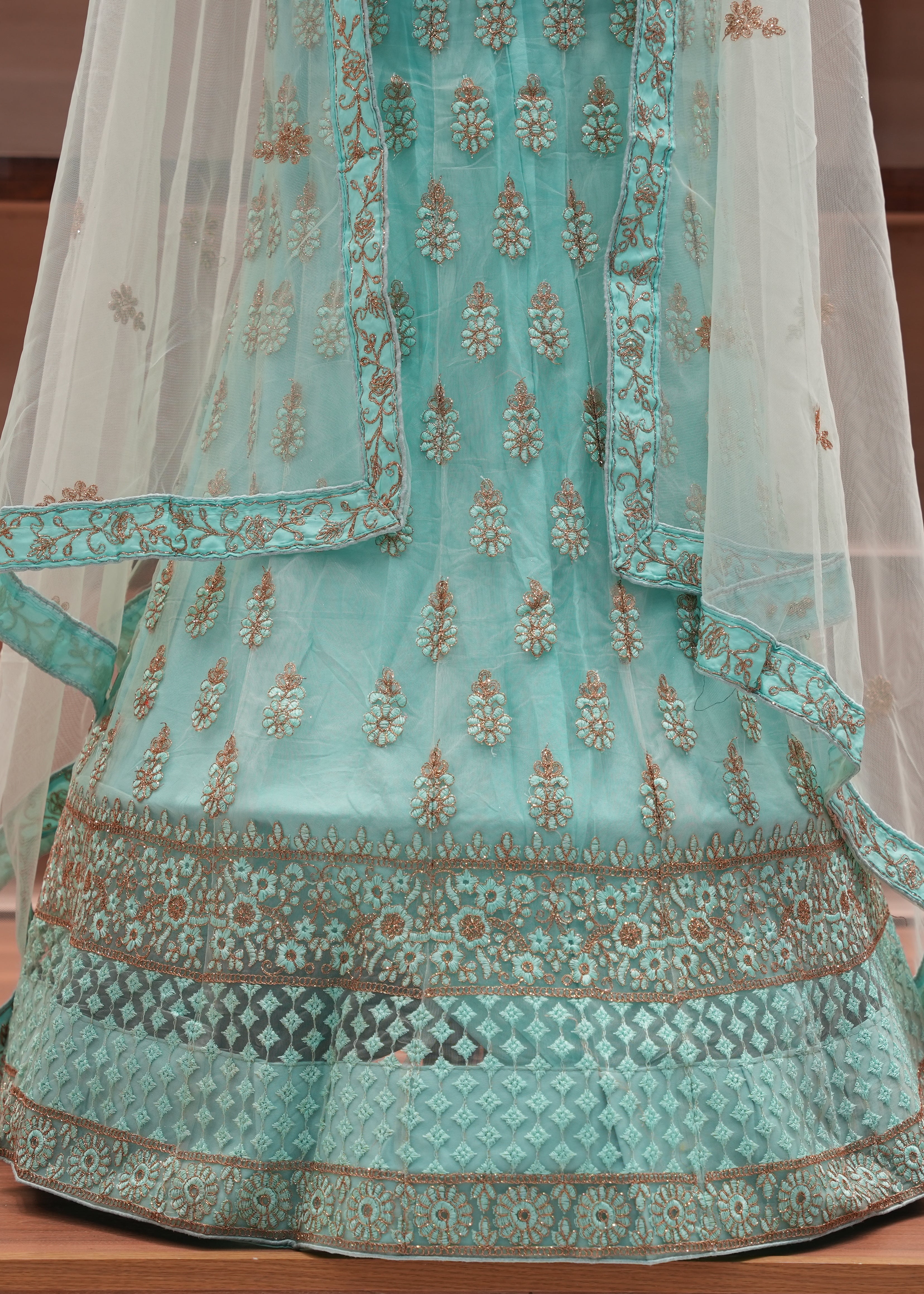 Turquoise embroidered traditional outfit with a sheer dupatta on a wooden surface