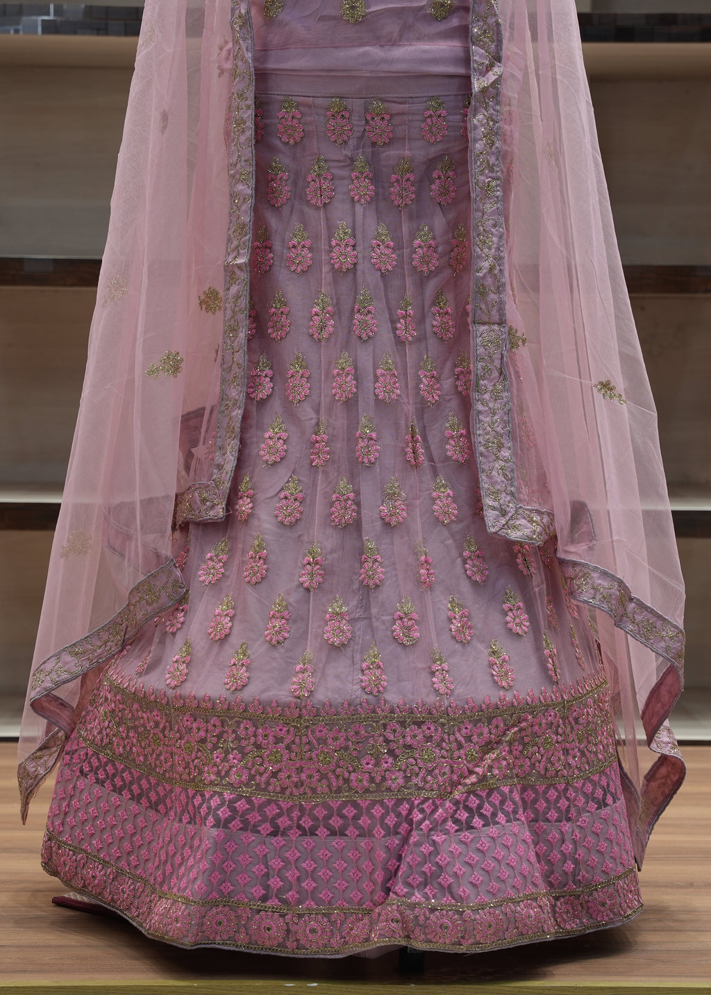 Pink embroidered traditional outfit with a sheer dupatta on a wooden surface.