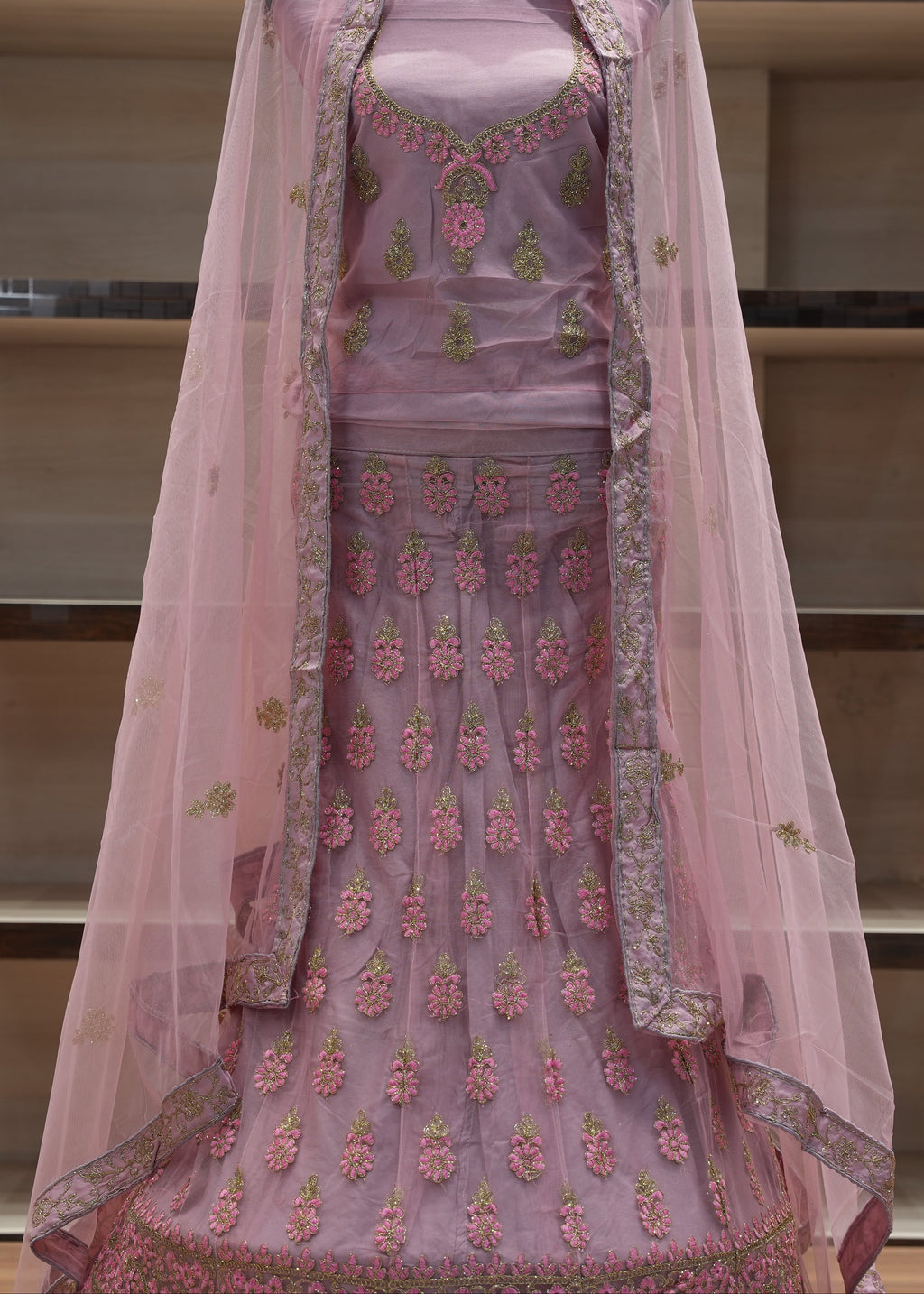 Pink embroidered traditional outfit with a sheer dupatta on a mannequin against a neutral background.