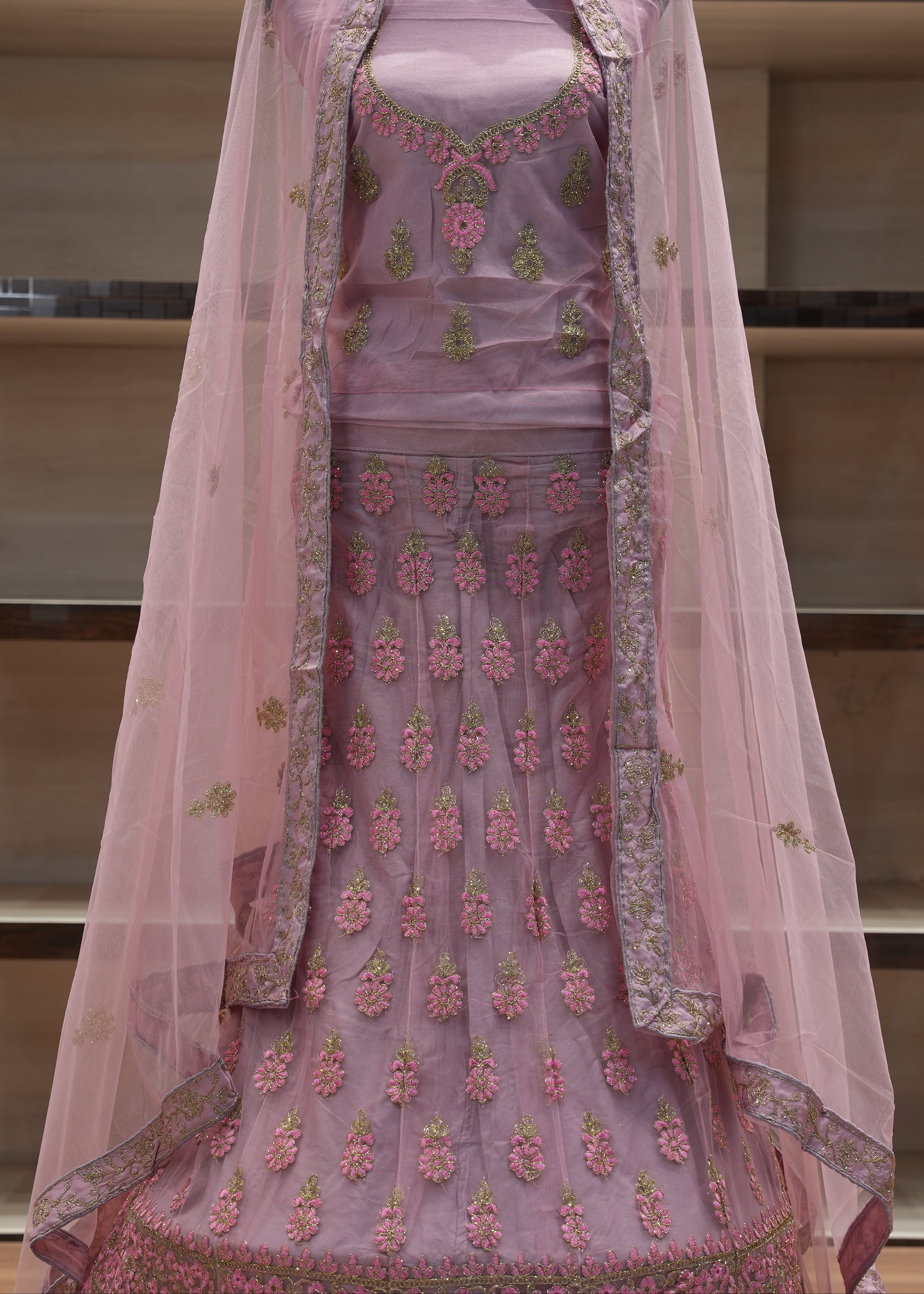 Pink embroidered traditional outfit with a sheer dupatta on a mannequin against a neutral background.