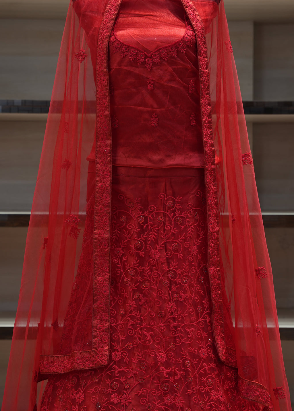 Red embroidered traditional outfit with a sheer overlay on a neutral background