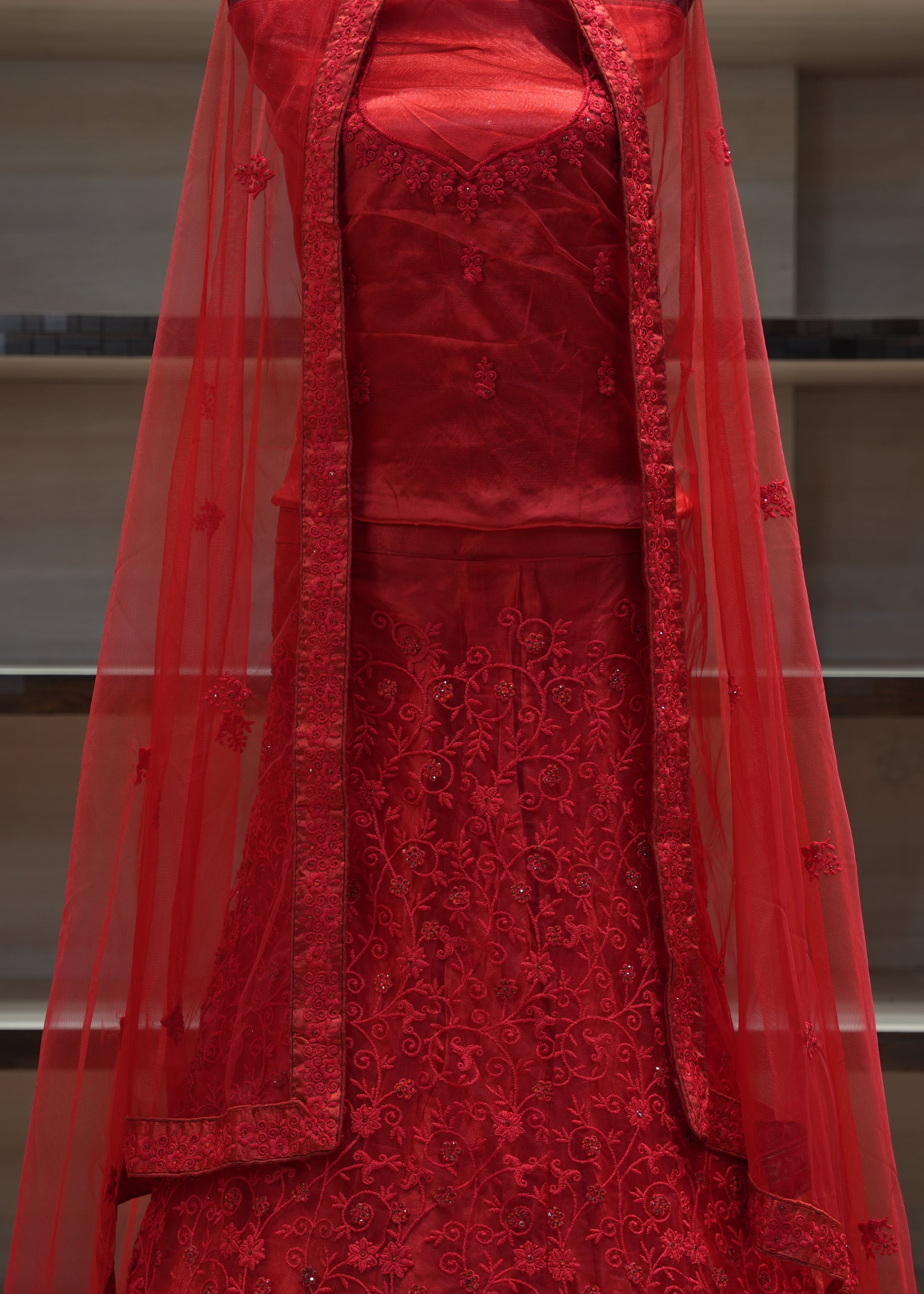 Red embroidered traditional outfit with a sheer overlay on a neutral background
