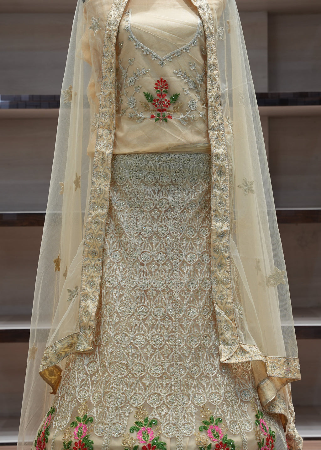 Traditional embroidered outfit with a sheer dupatta in a neutral setting