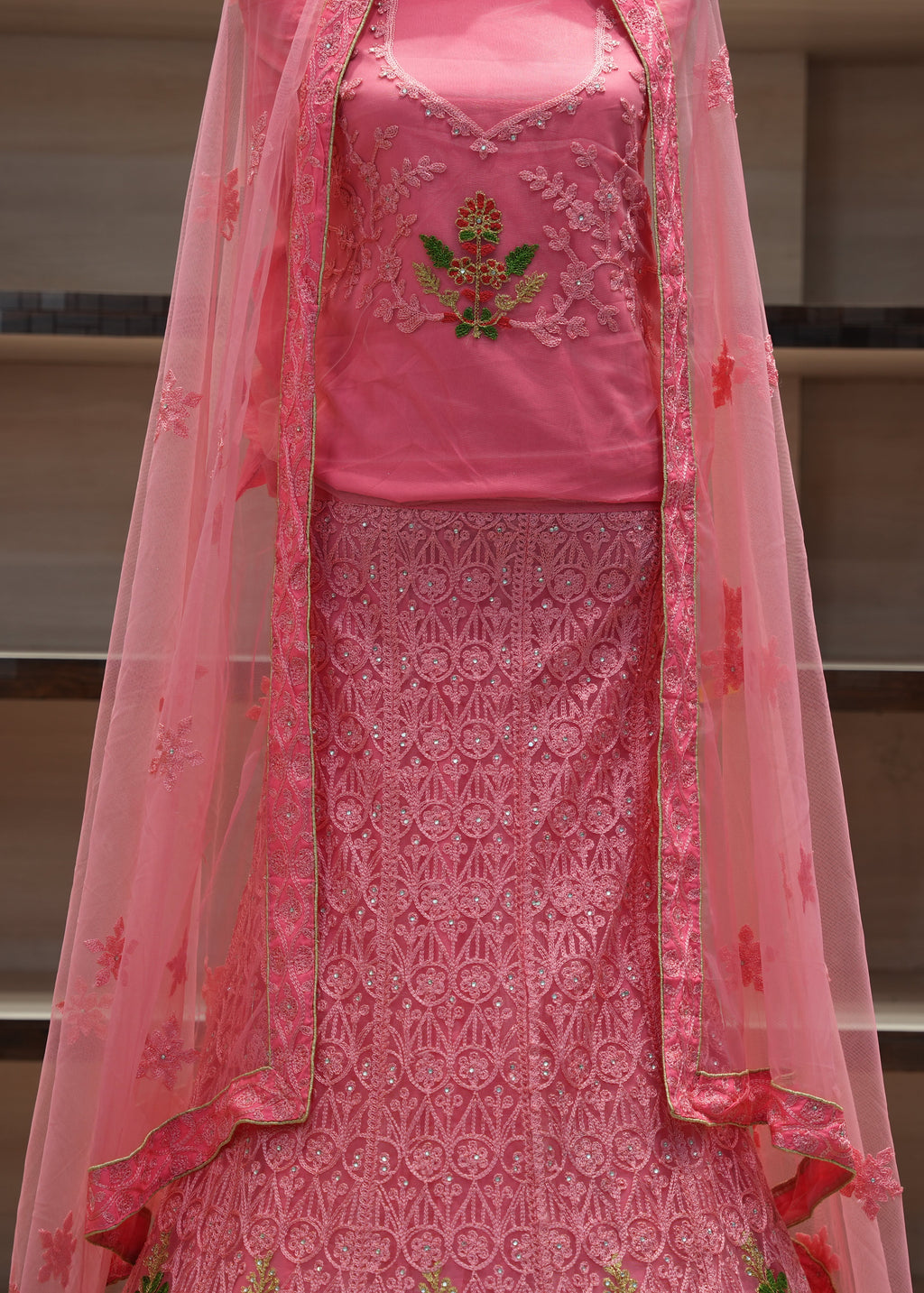 Pink embroidered traditional outfit with a sheer dupatta on a neutral background