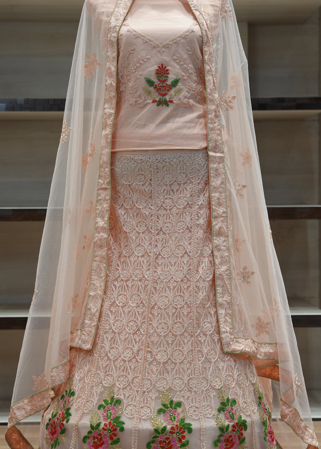 Traditional embroidered outfit with a sheer dupatta on a neutral background