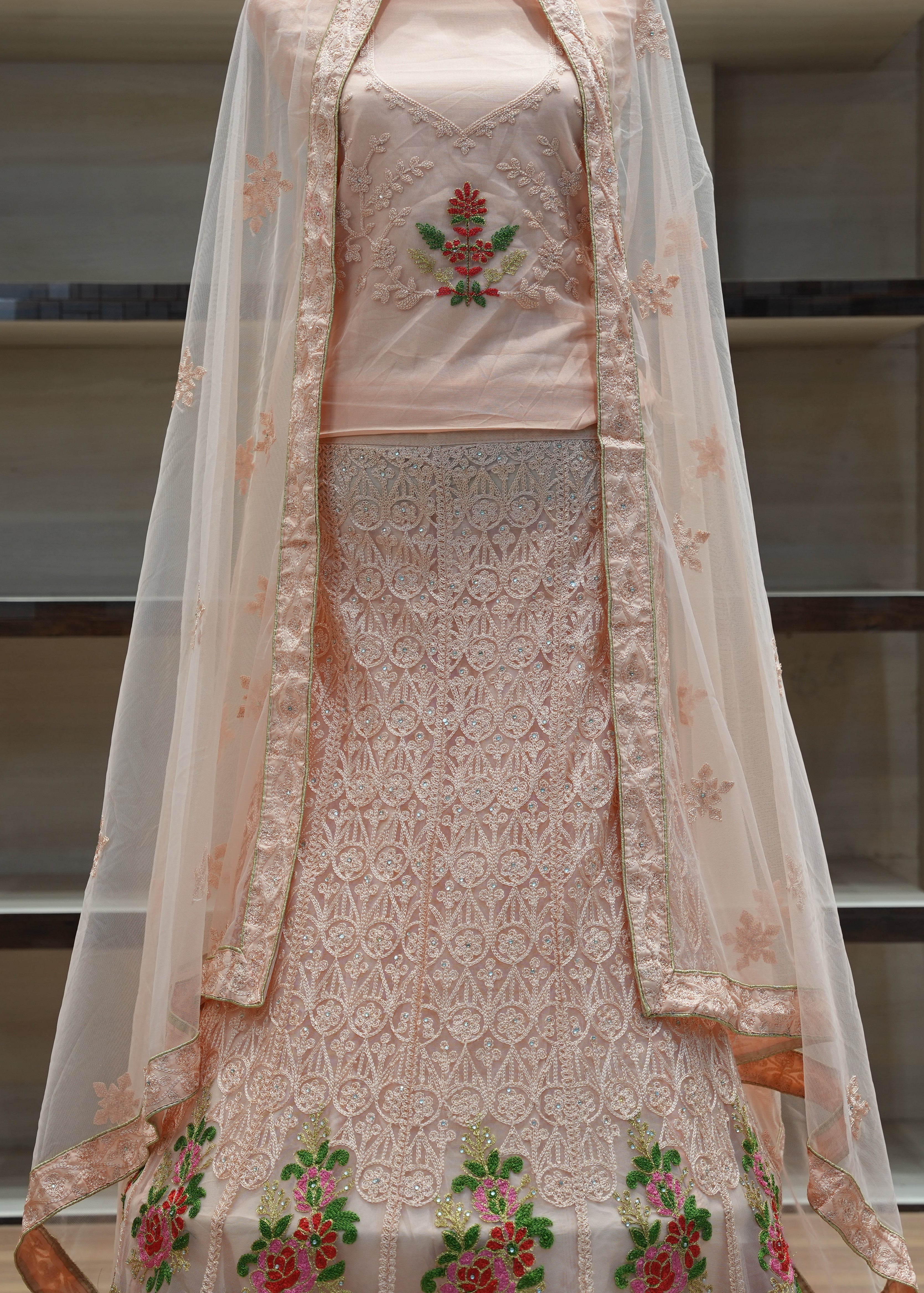 Traditional embroidered outfit with a sheer dupatta on a neutral background