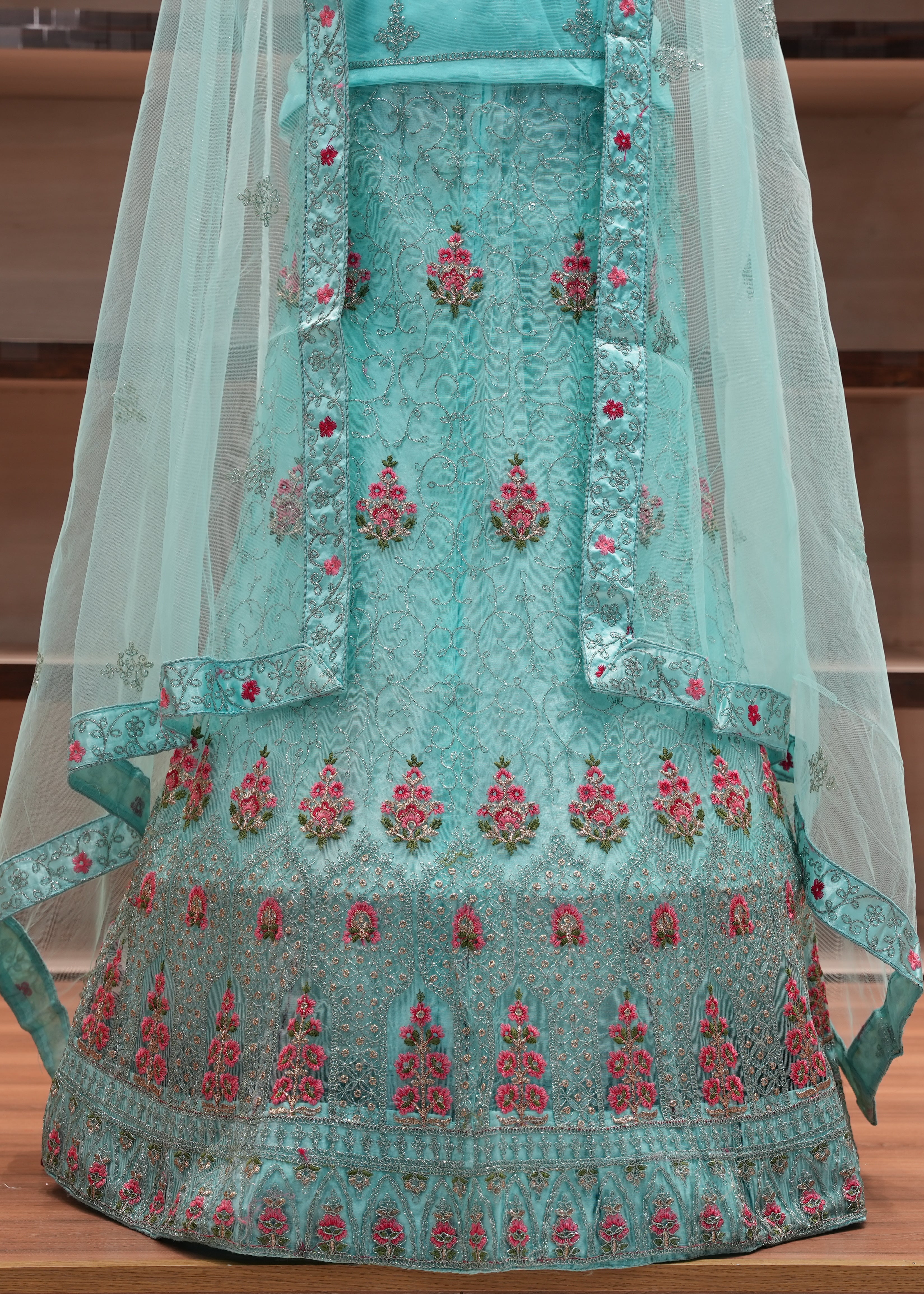 Teal embroidered traditional outfit with a sheer dupatta on a wooden surface.