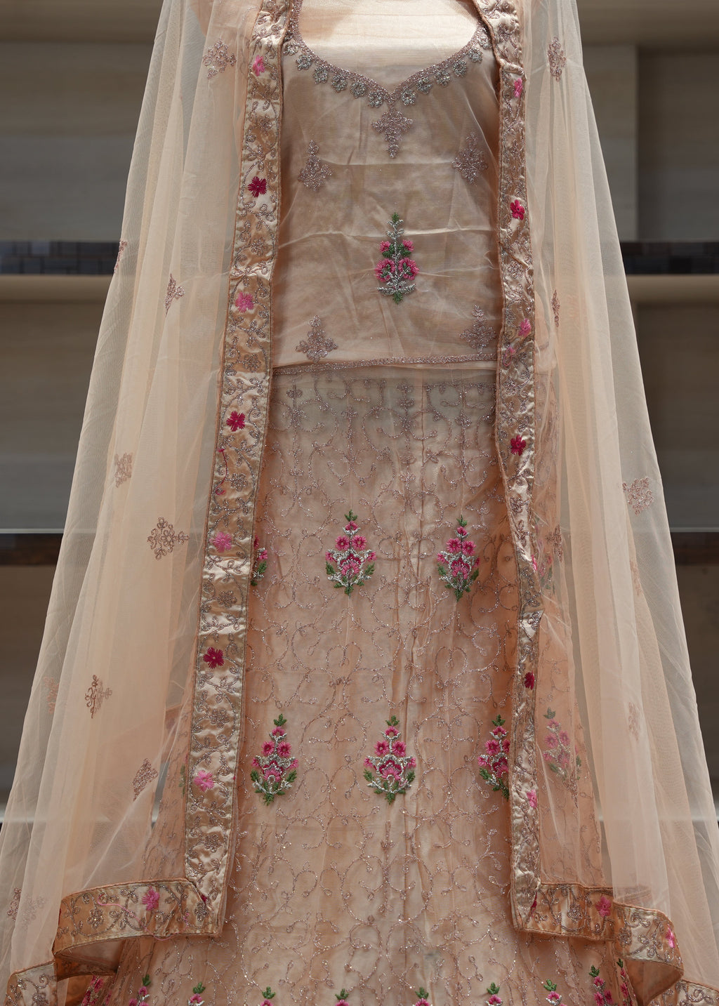 Beige embroidered traditional outfit with a sheer dupatta on a neutral background