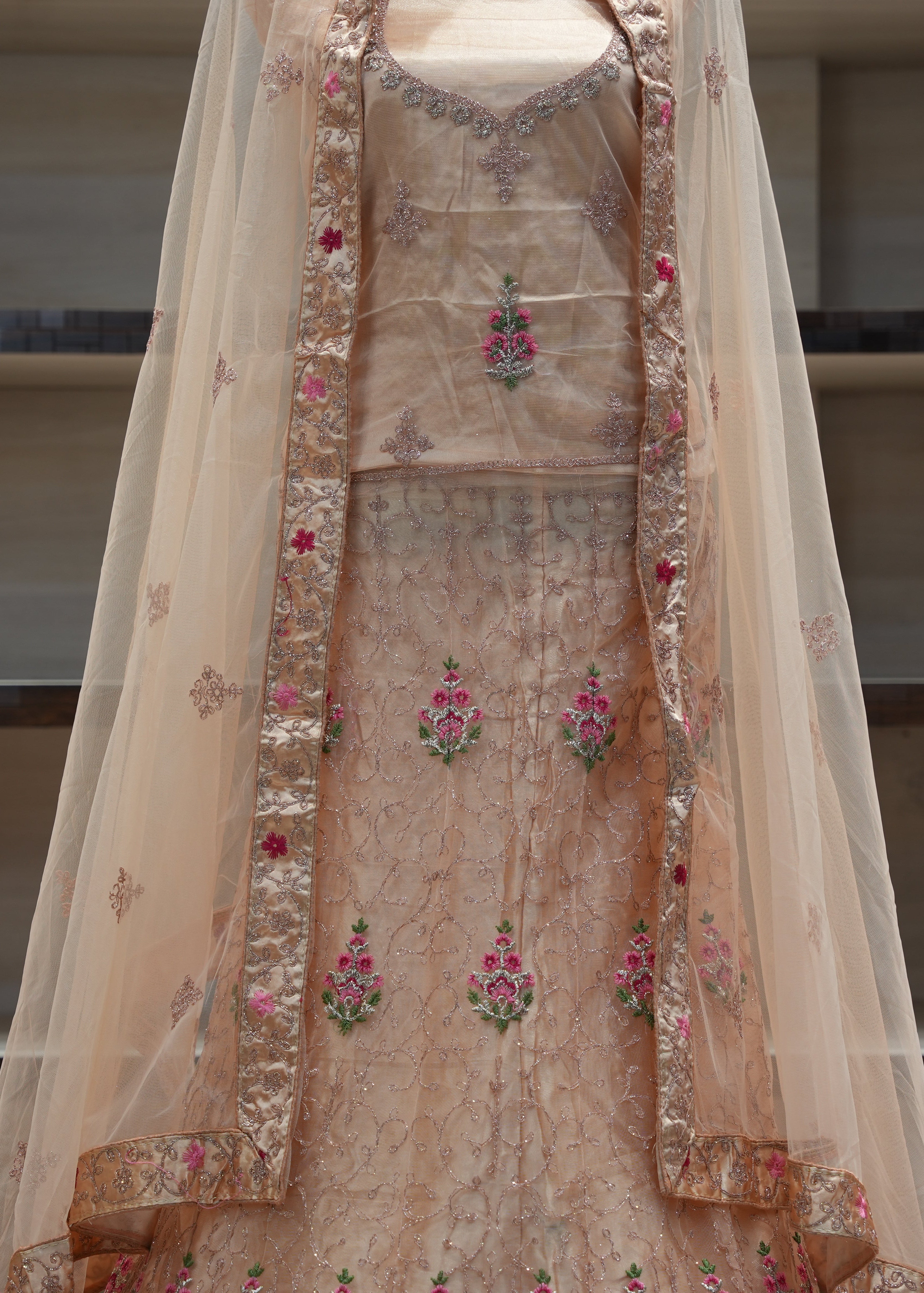 Beige embroidered traditional outfit with a sheer dupatta on a neutral background