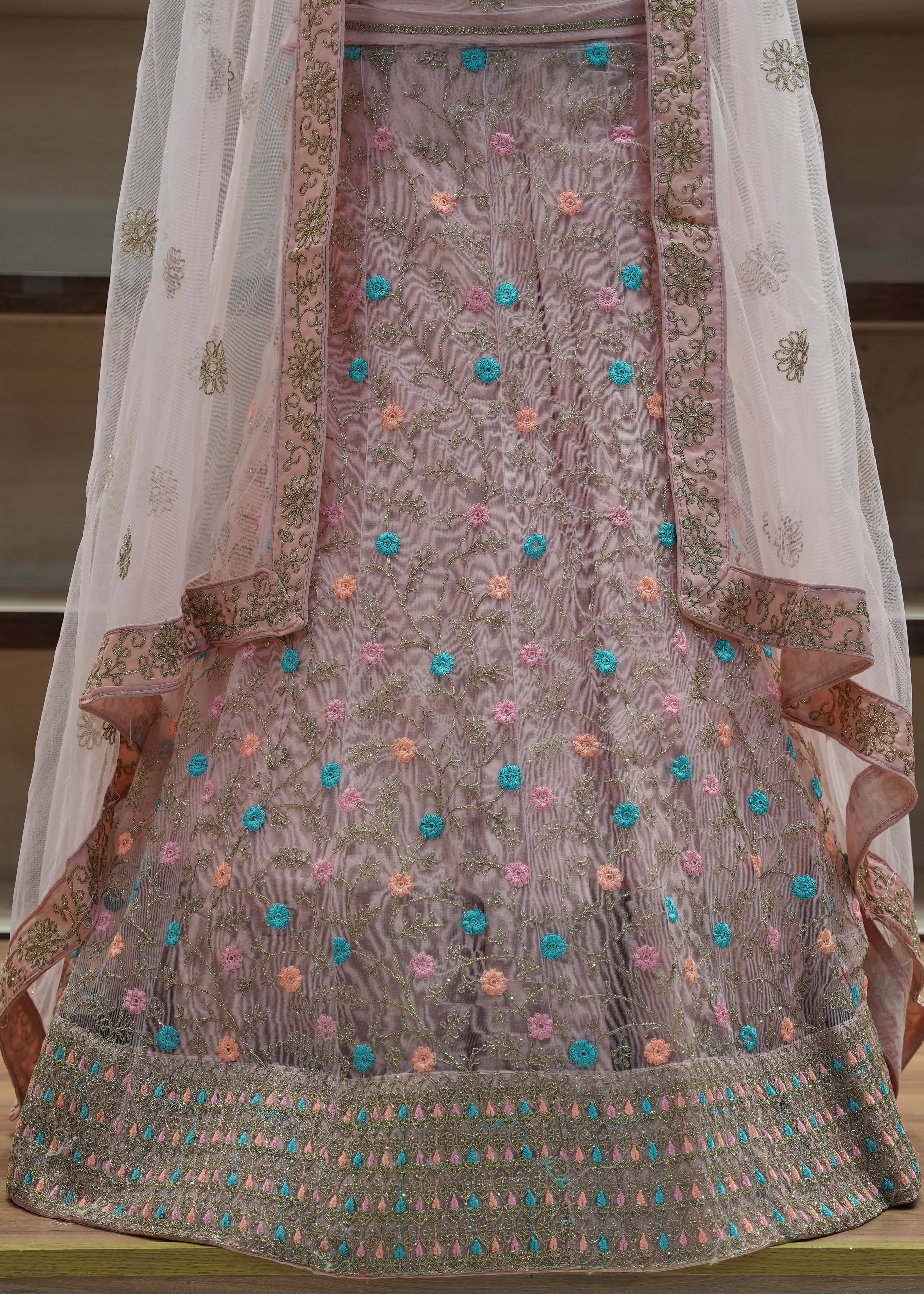 Traditional embroidered outfit with a sheer dupatta on a wooden surface