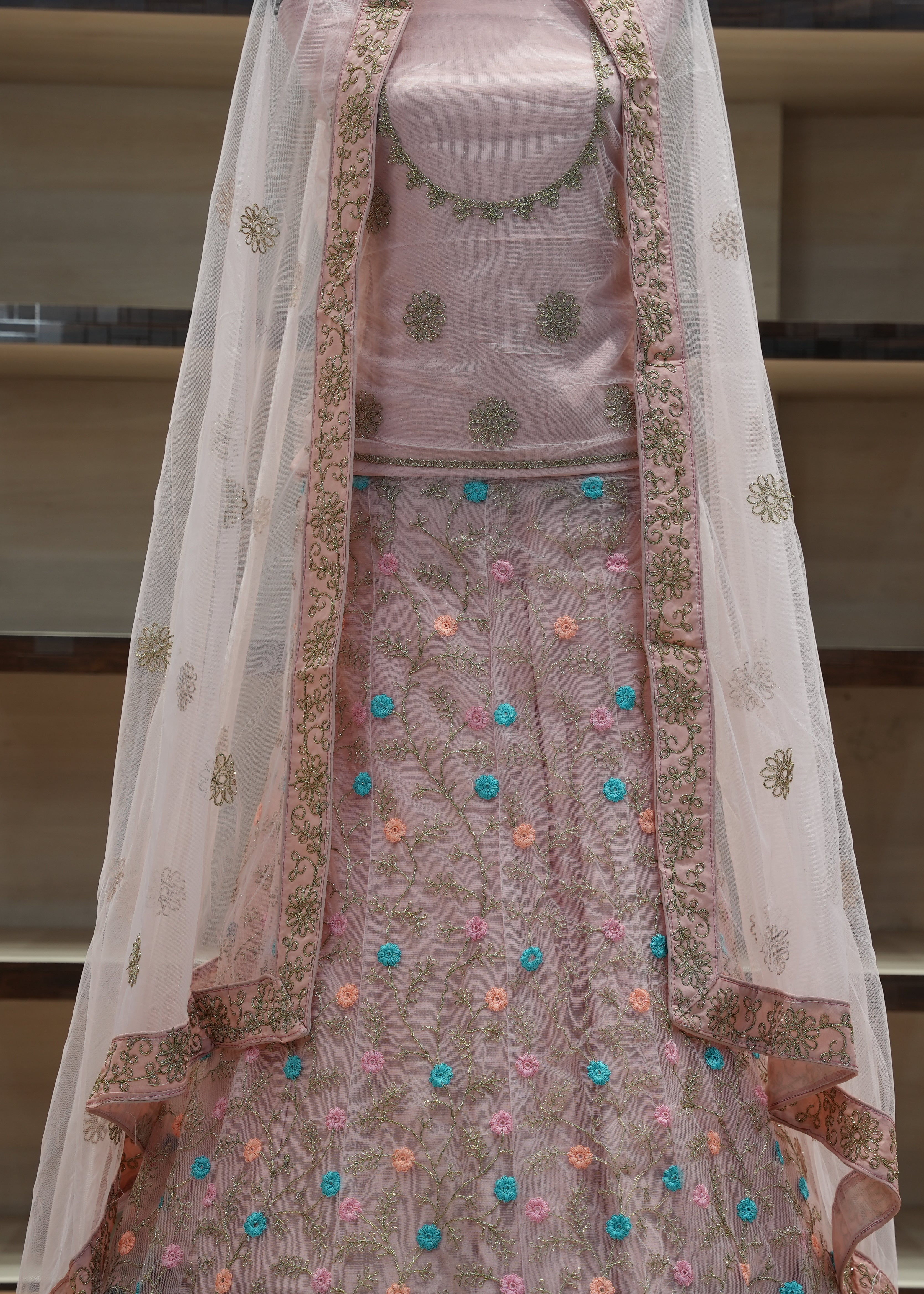 Traditional pink embroidered outfit with a sheer dupatta on a neutral background
