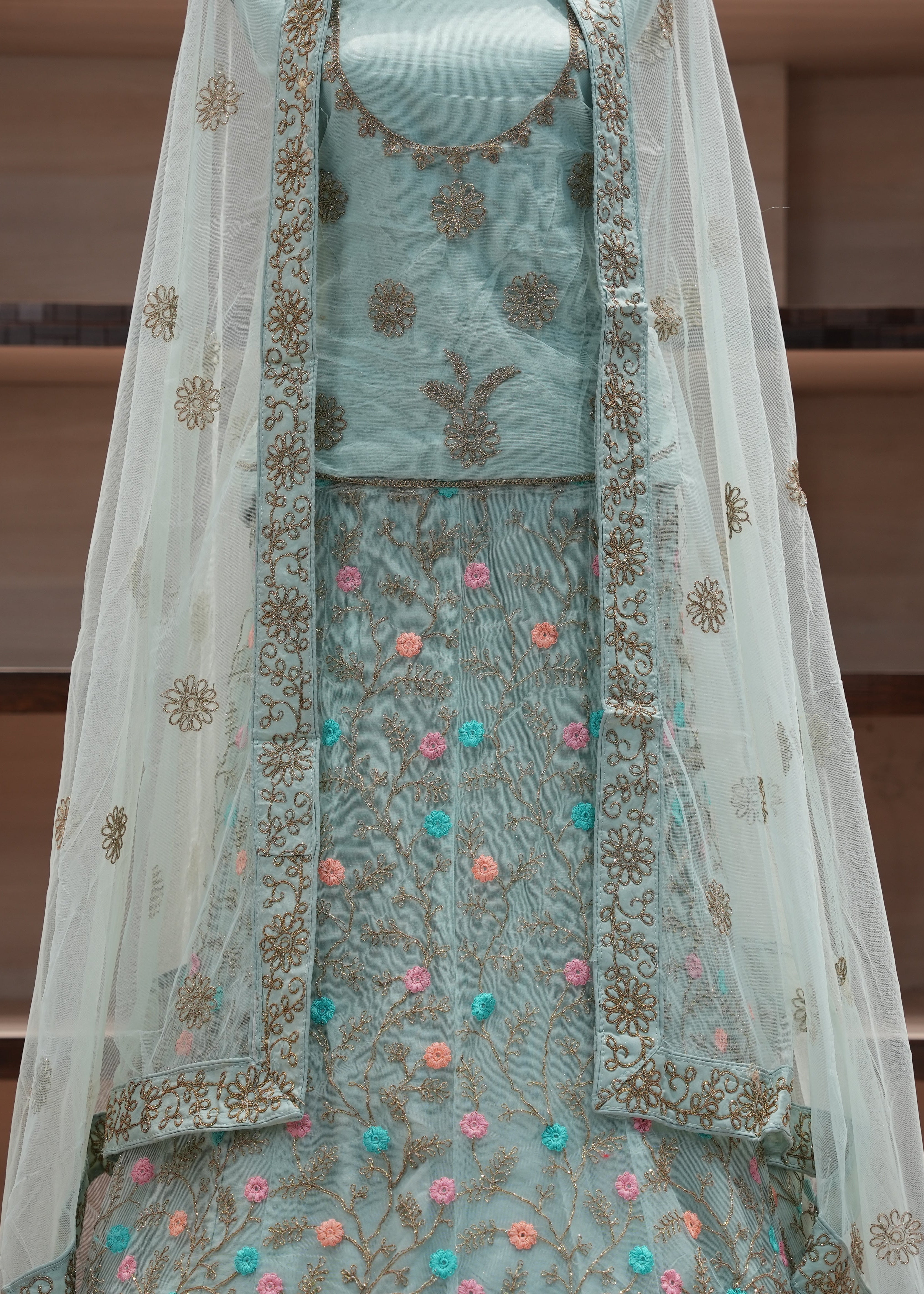 Light blue embroidered traditional outfit with a sheer dupatta on a wooden shelf background